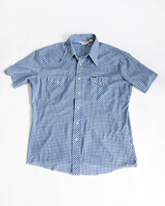 a vintage 1980s blue checkered pearl snap Wrangler shirt on a white background