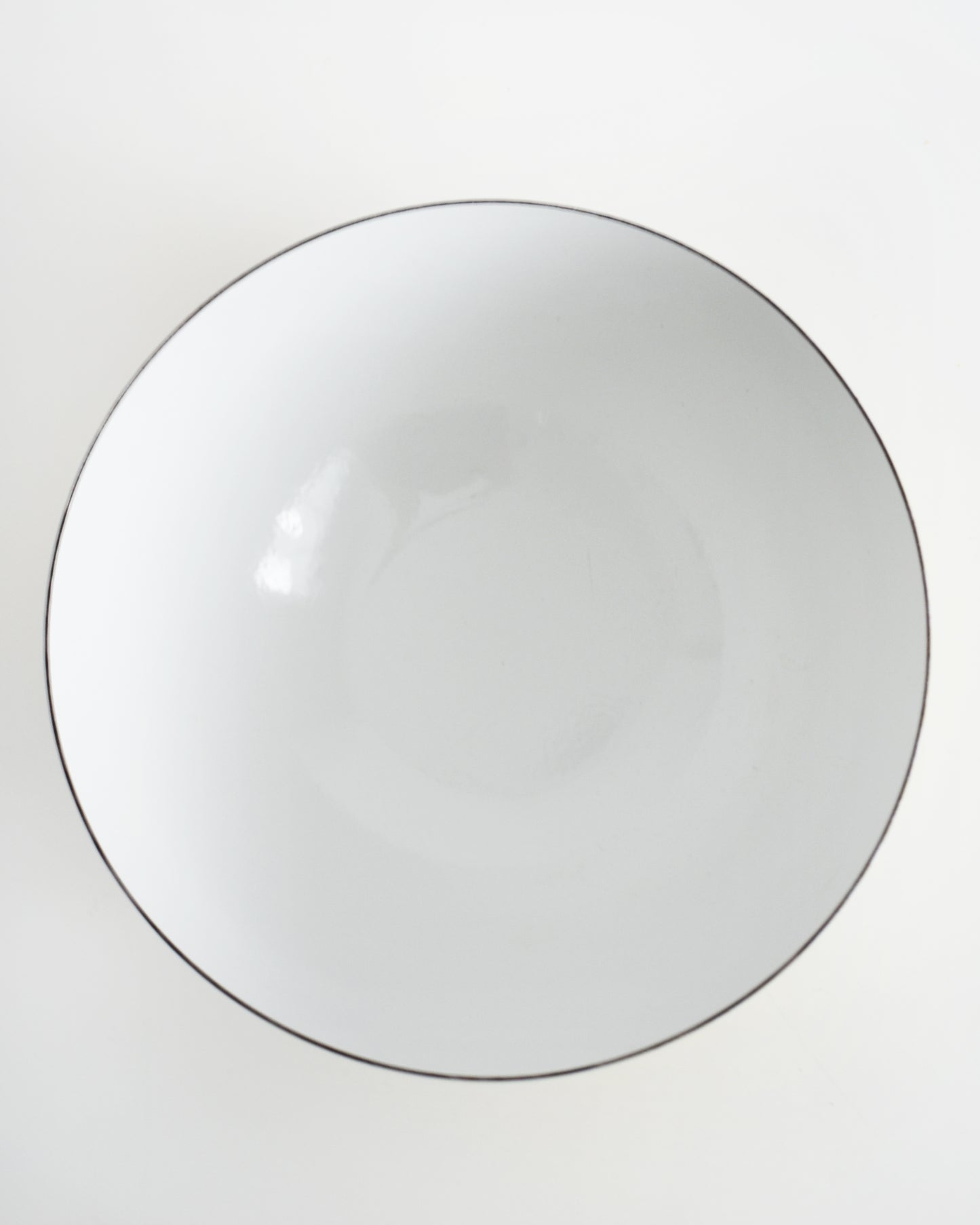 overhead shot of a vintage yellow and white striped Cathrineholm bowl on a white background