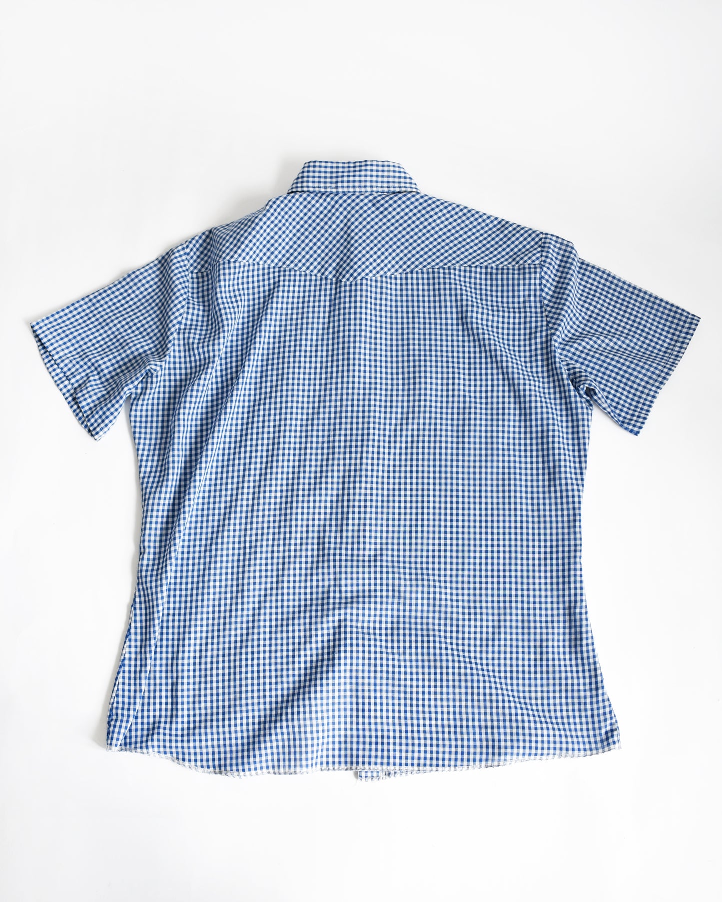 back view of a vintage 1980s blue checkered pearl snap Wrangler shirt on a white background