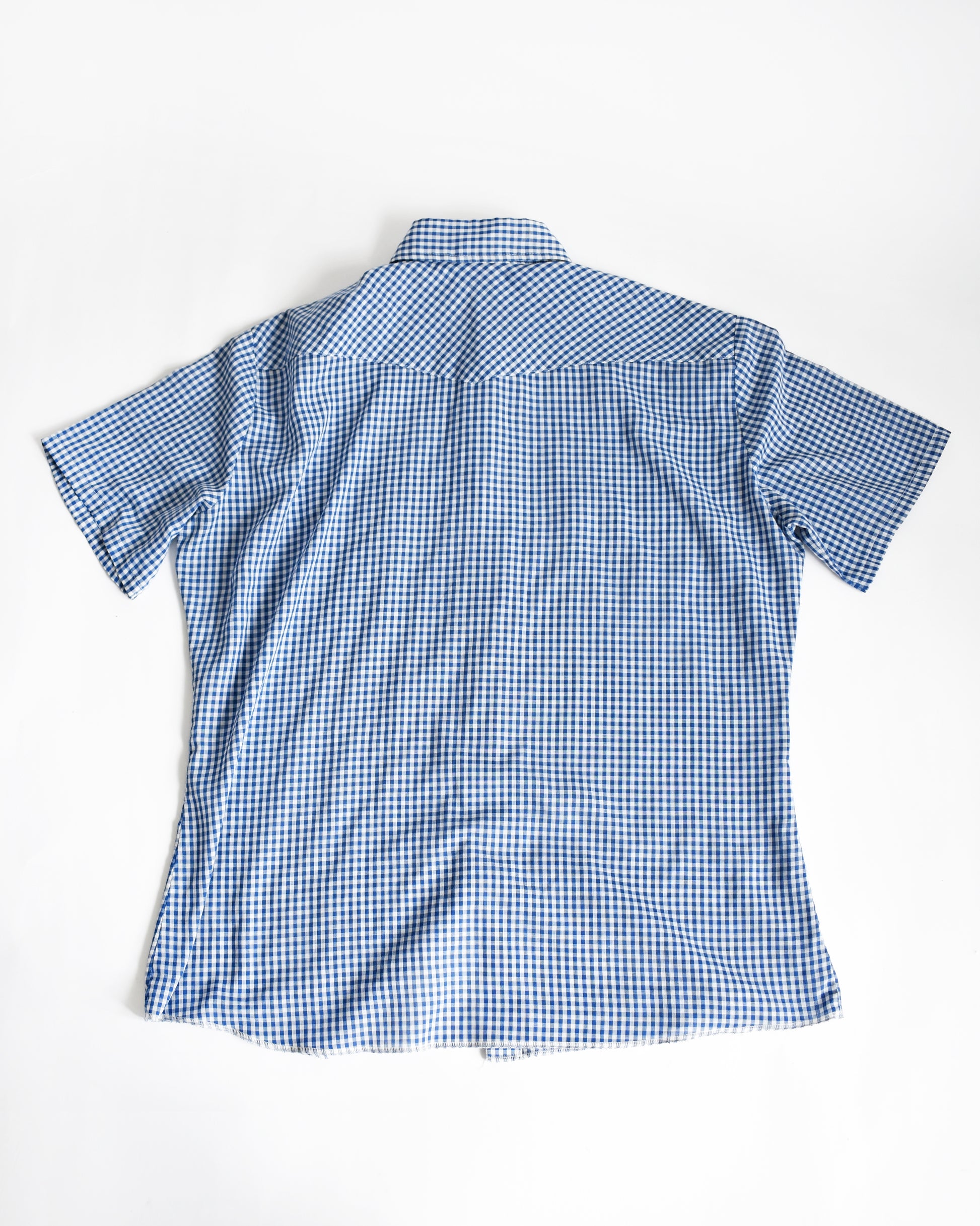 back view of a vintage 1980s blue checkered pearl snap Wrangler shirt on a white background