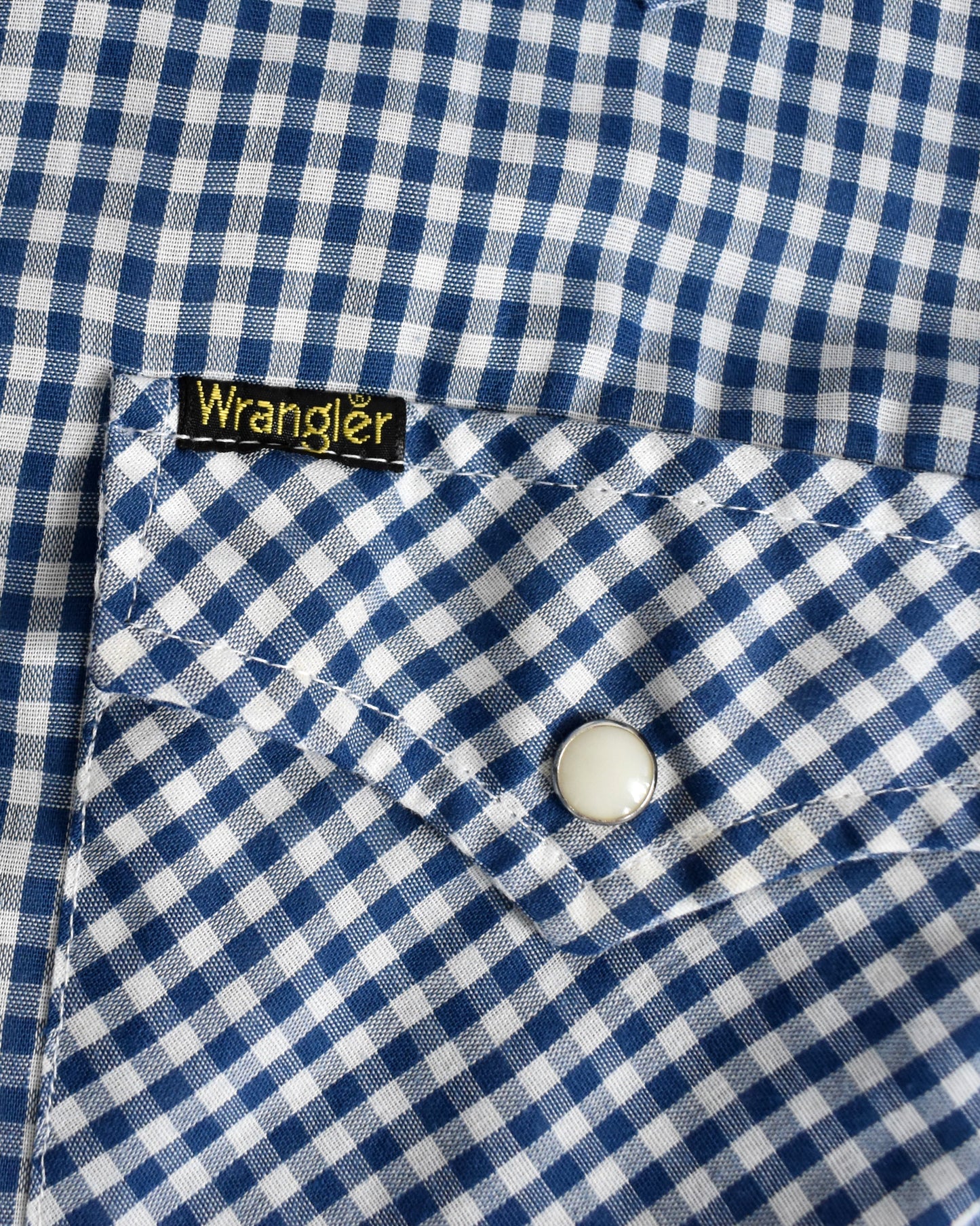 Close-up of a blue and white checkered shirt with a Wrangler label.