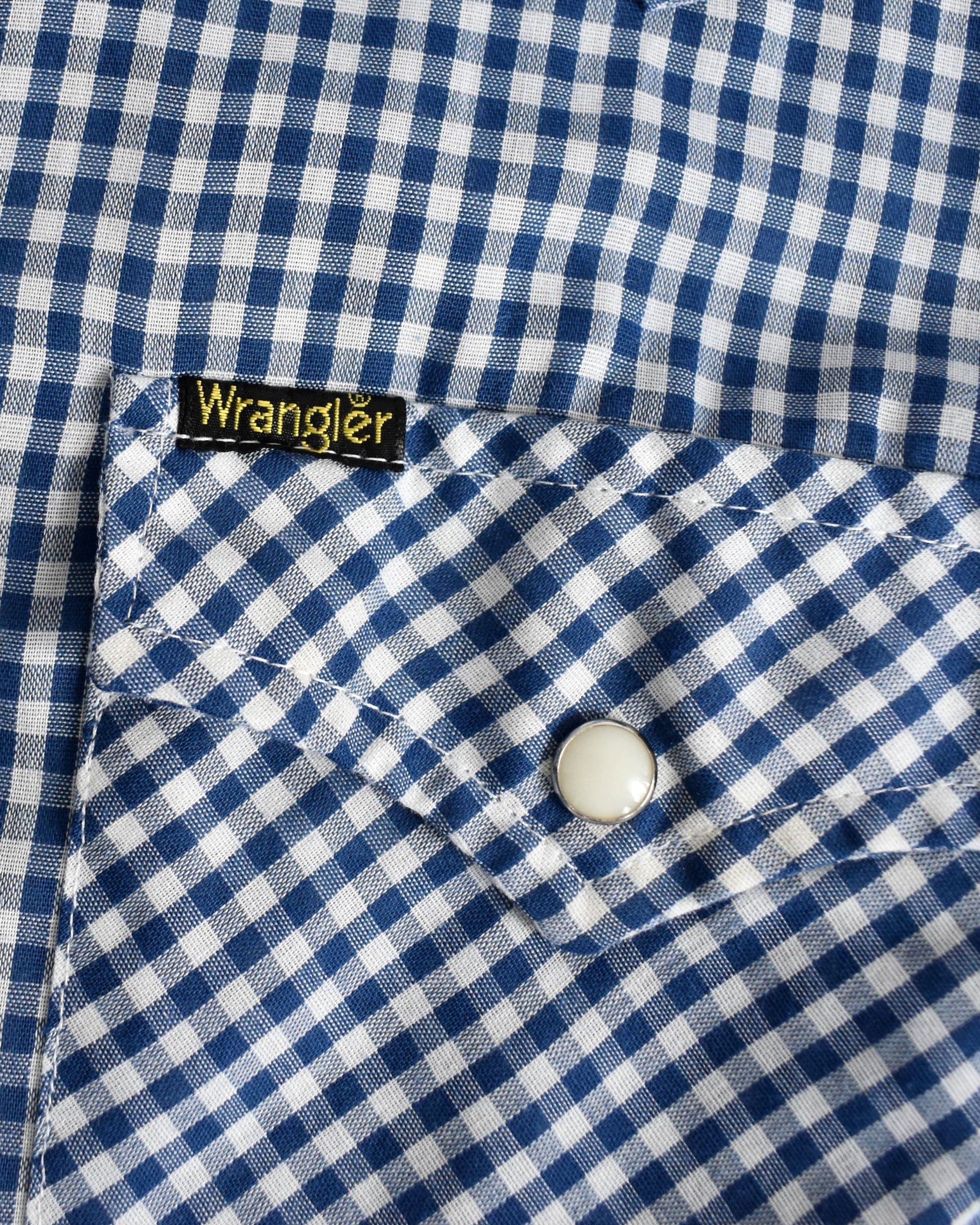 Close-up of a blue and white checkered shirt with a Wrangler label.
