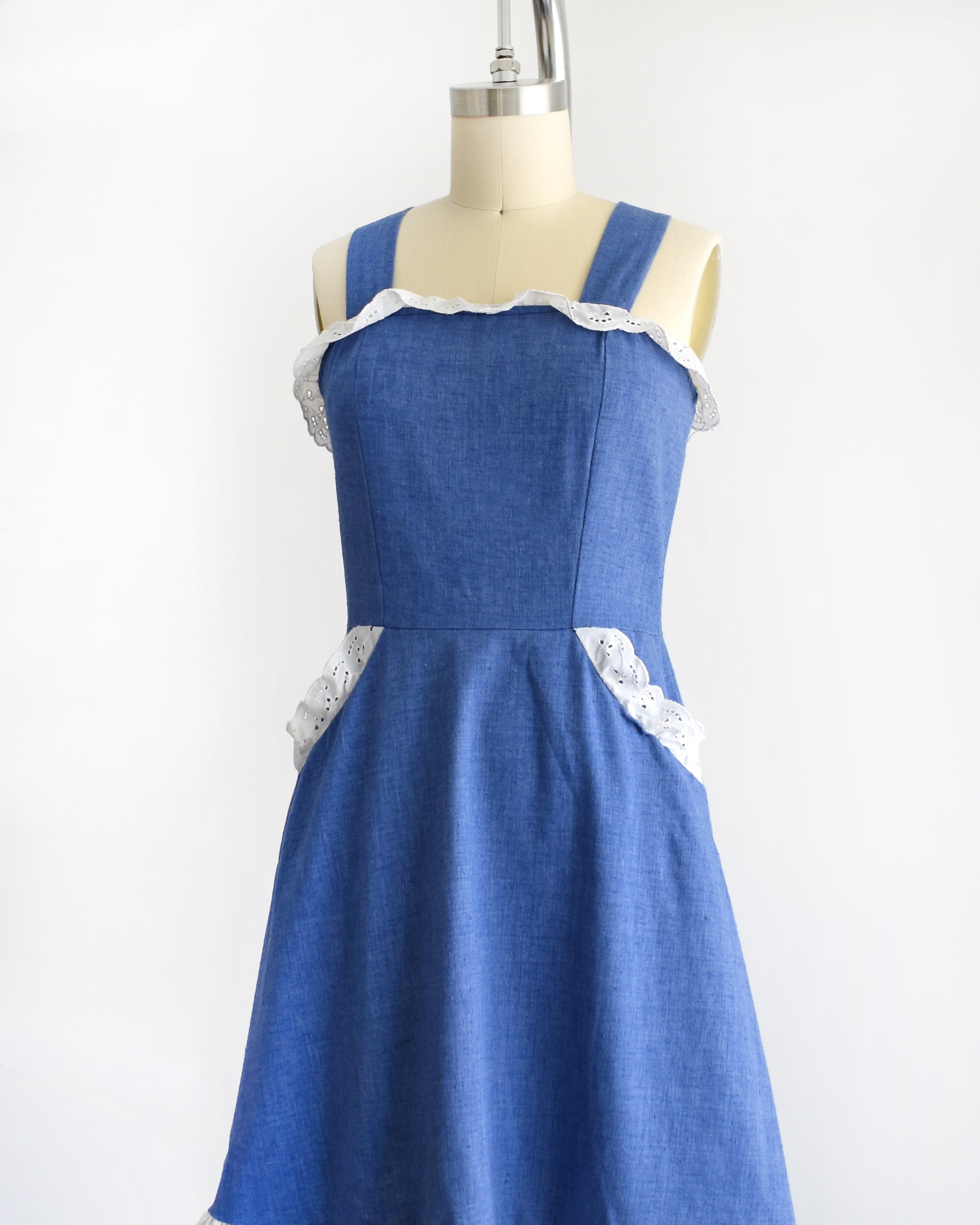 side front view of a vintage 1970s blue dress with white lace details on a mannequin against a white background