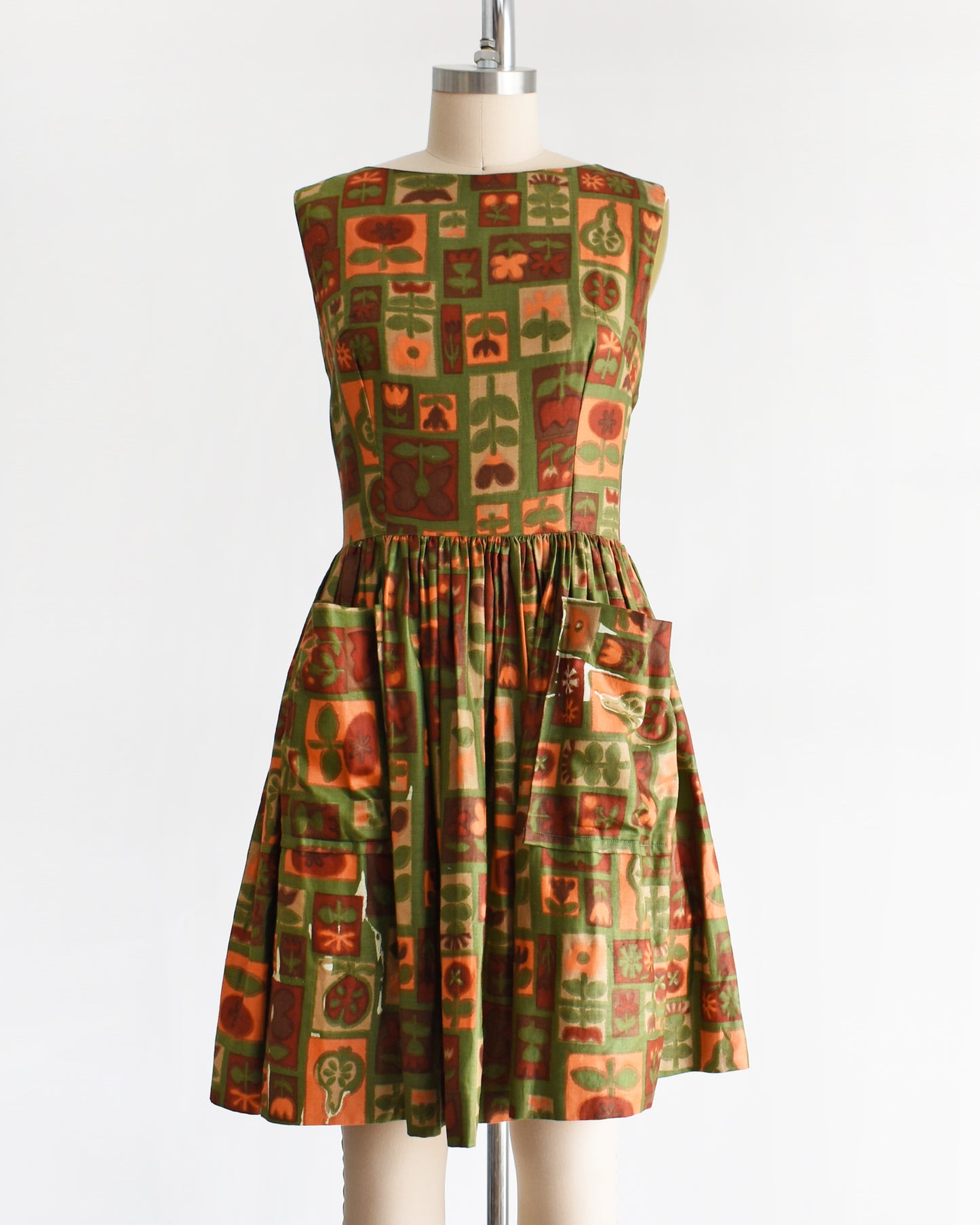 a vintage 1960s fruits and florals patterned dress on a mannequin against a white background
