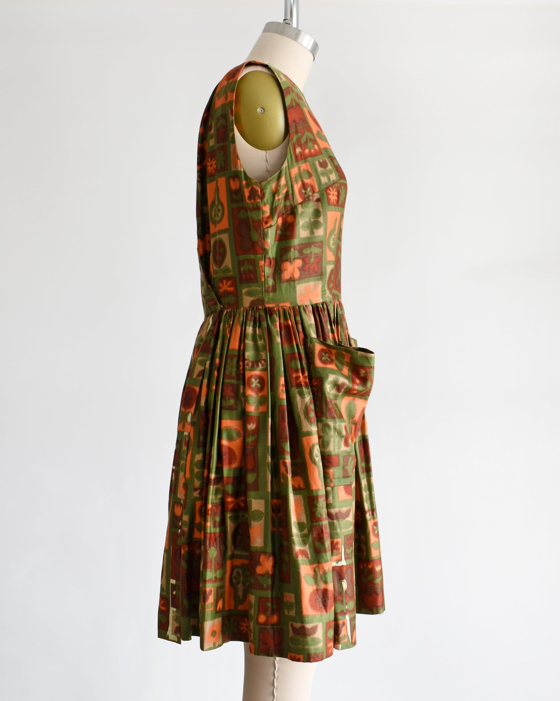 side view of a vintage 1960s fruits and florals patterned dress on a mannequin against a white background