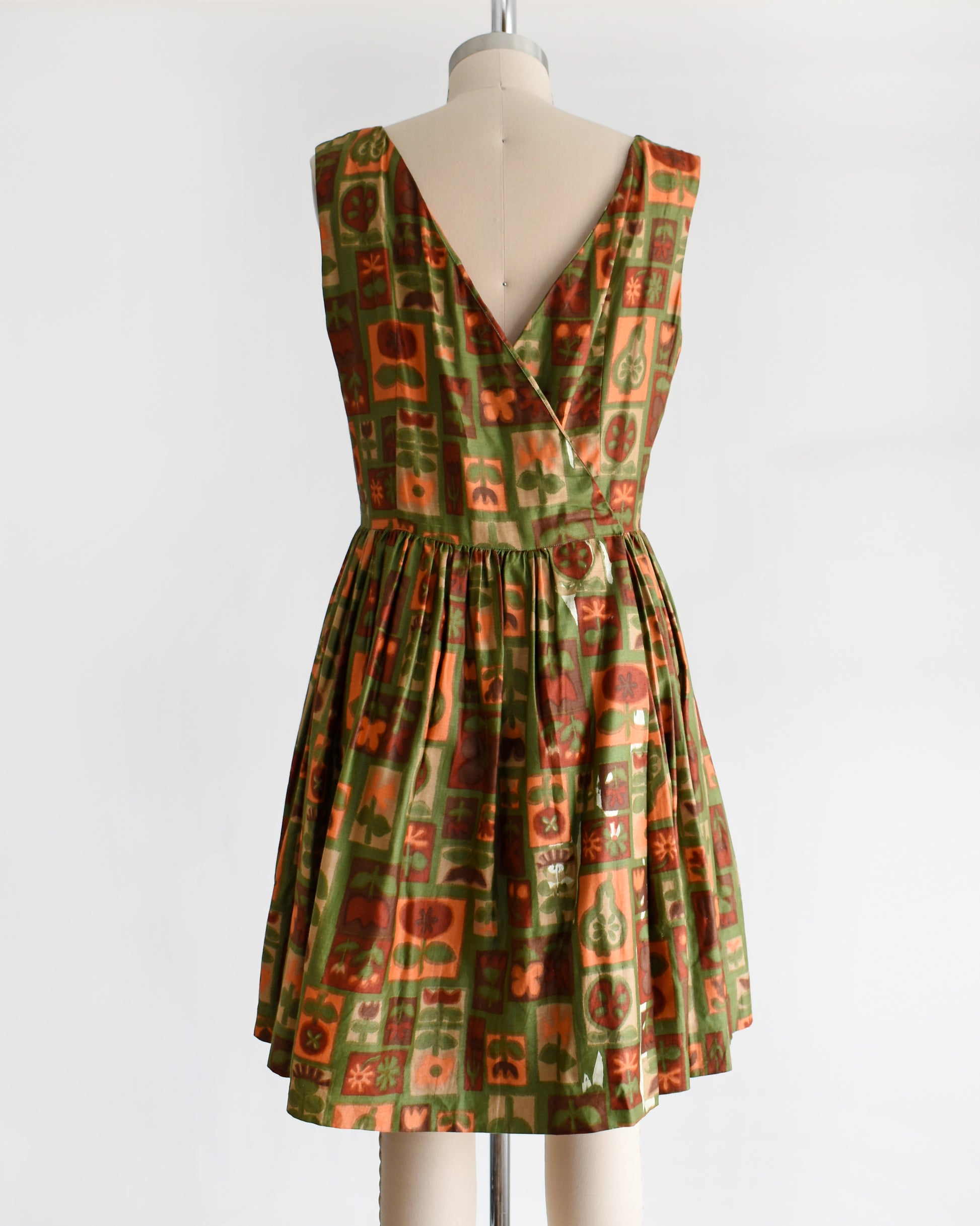 back view of a vintage 1960s fruits and florals patterned dress on a mannequin against a white background