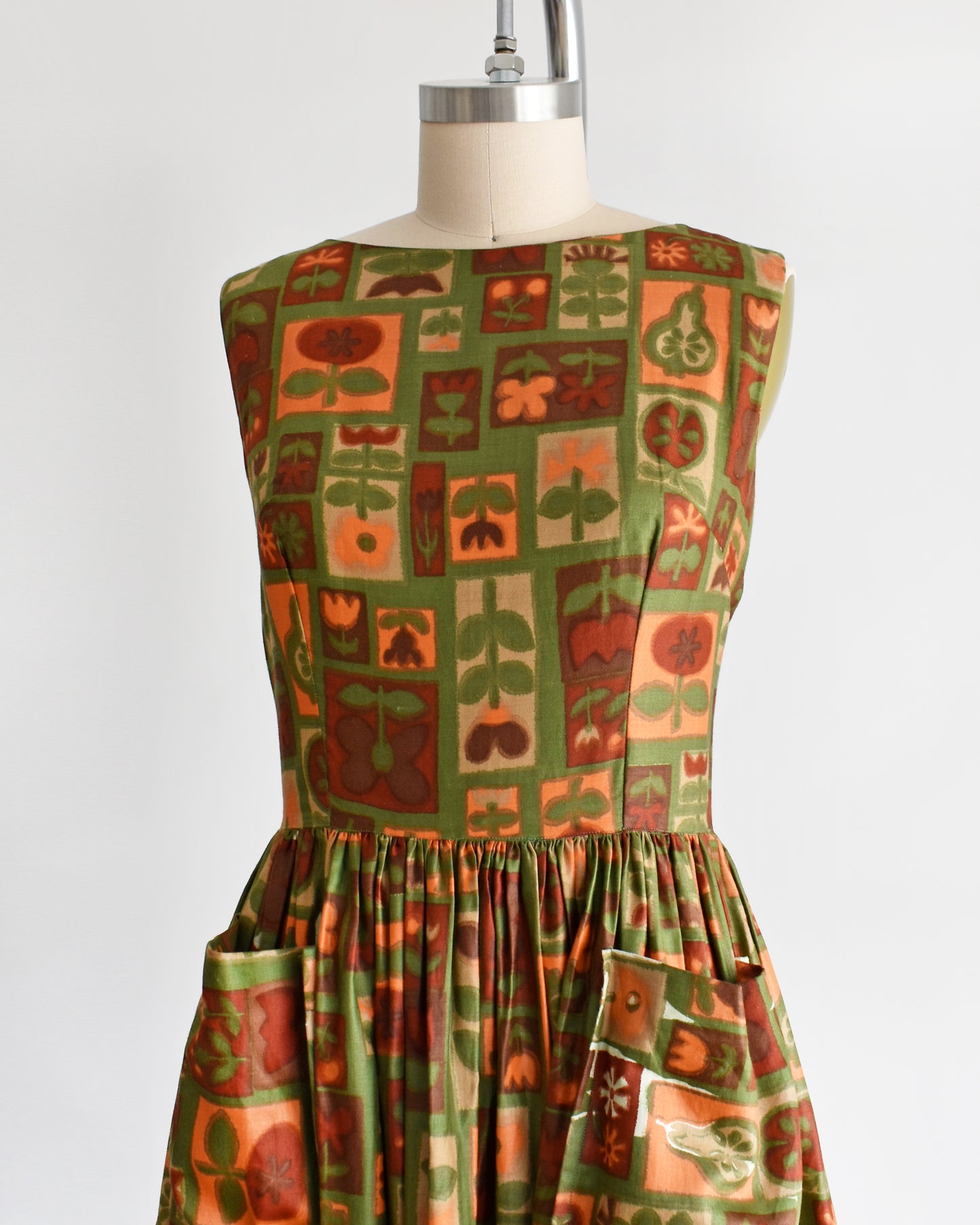 side front view of a vintage 1960s fruits and florals patterned dress on a mannequin against a white background