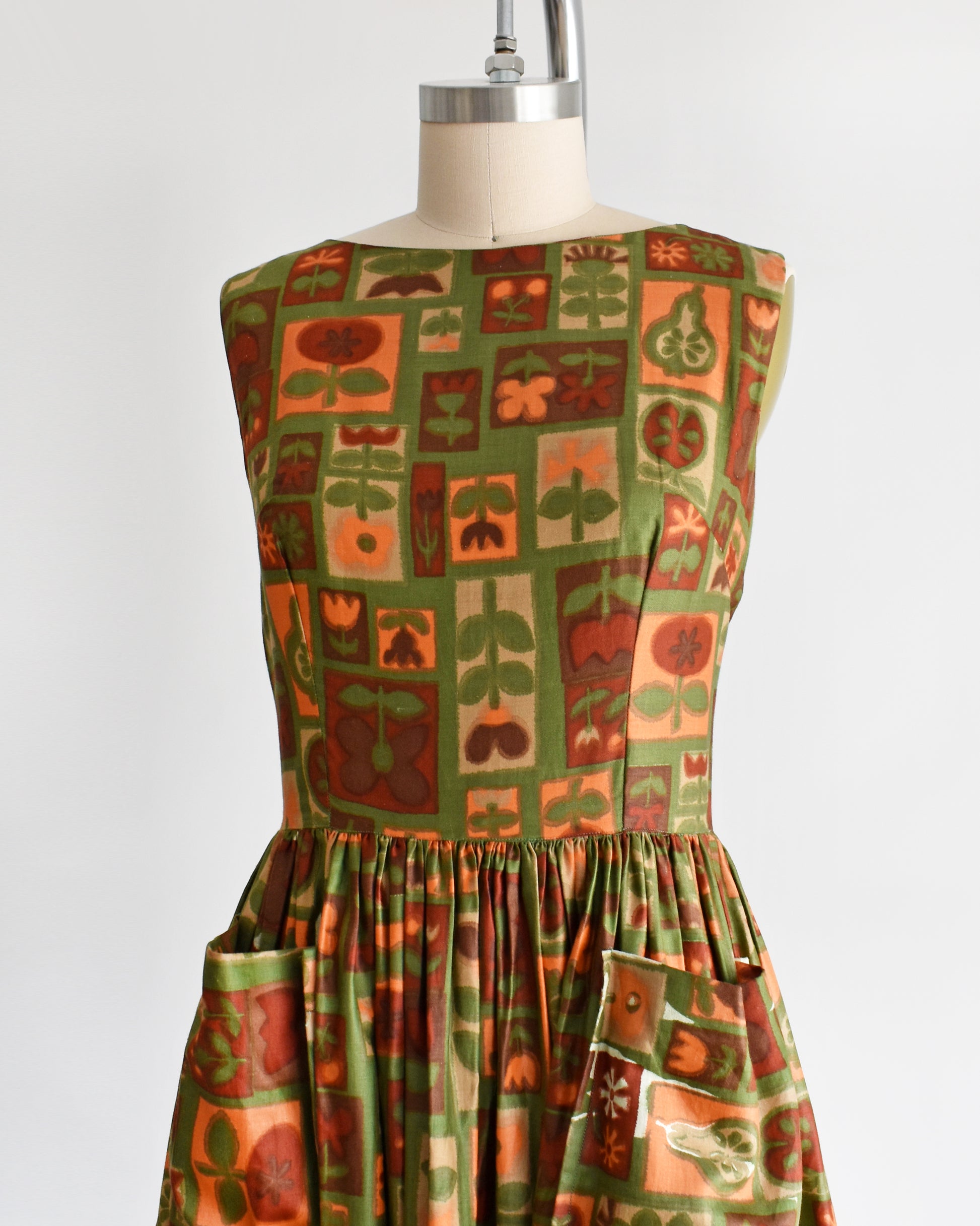 side front view of a vintage 1960s fruits and florals patterned dress on a mannequin against a white background