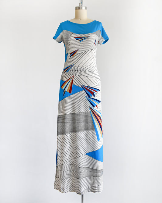 a vintage 1970s dress with geometric patterns and paper planes on a mannequin against a white background