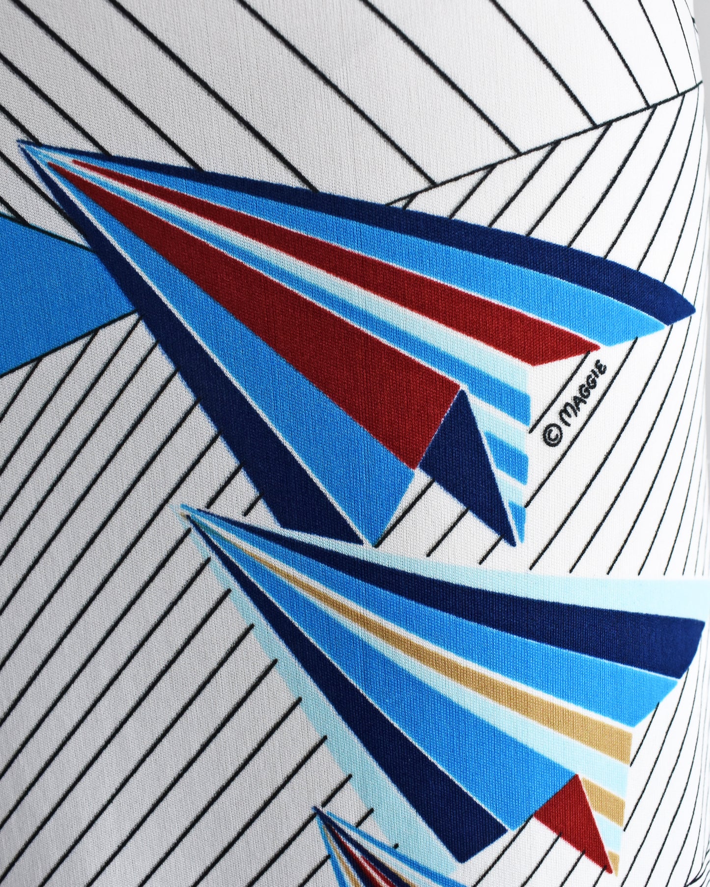 close up of the paper planes print and the "Maggie" logo