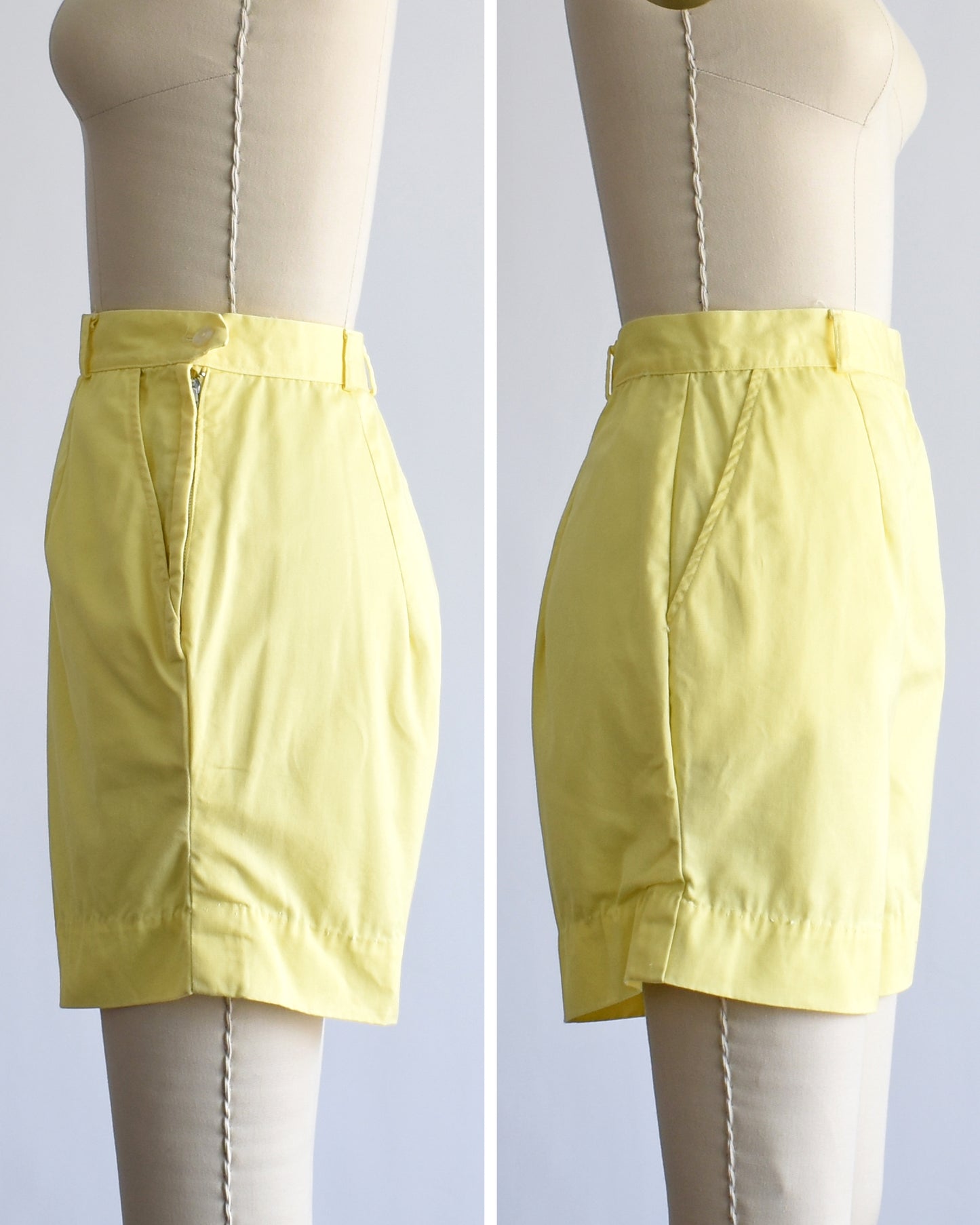 A pair of light yellow vintage high-waisted shorts displayed on a cream dress form, showing both side views against a light gray background.