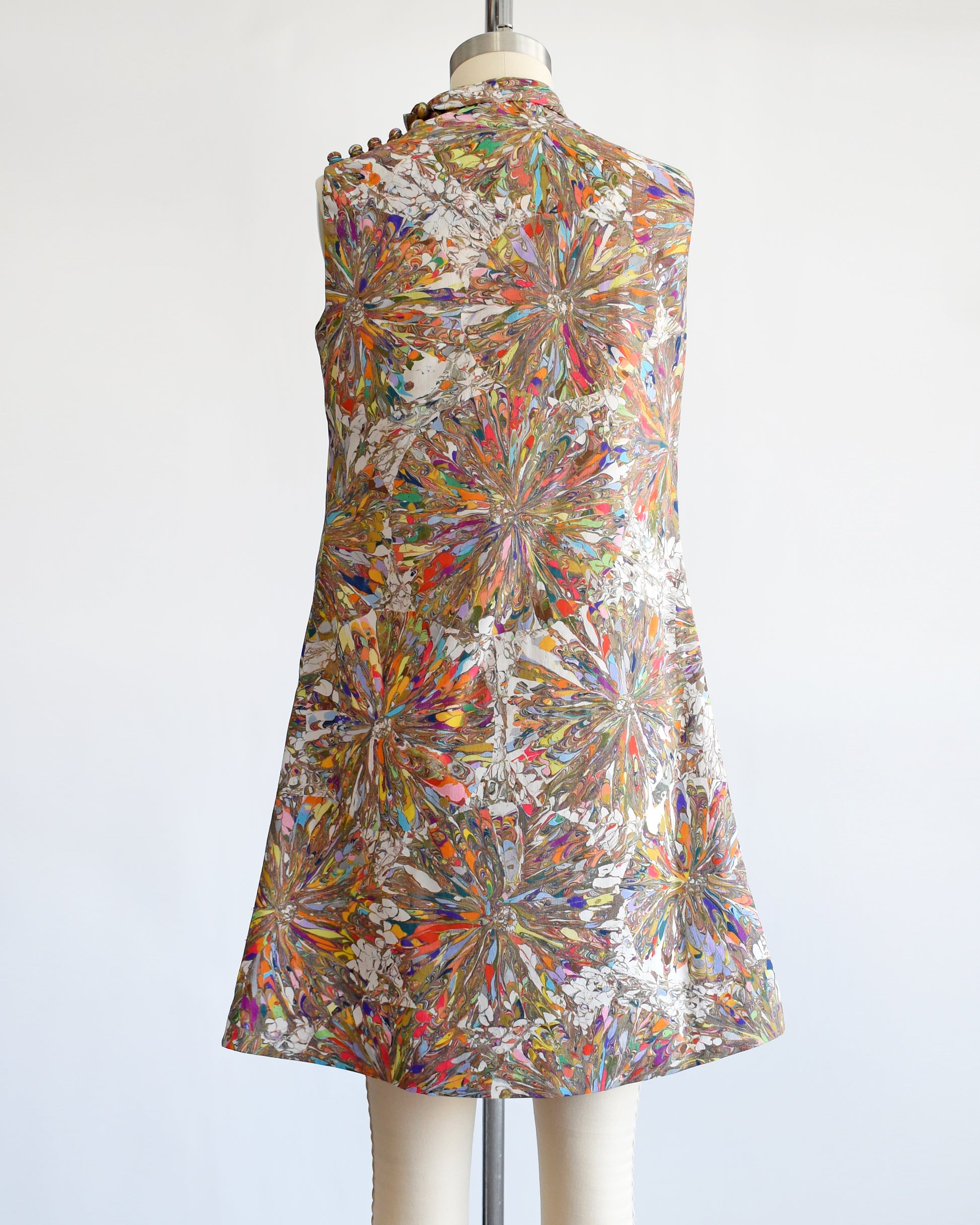 back views of a vintage 1960s mod mini dress that has a multicolored psychedelic kaleidoscope print