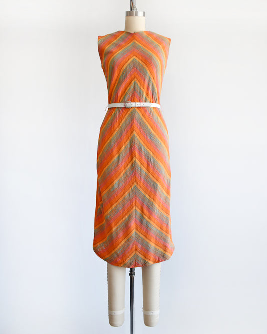 A vintage 1950s/1960s orange chevron rainbow striped dress with a white belt (belt not included) on a dress form 