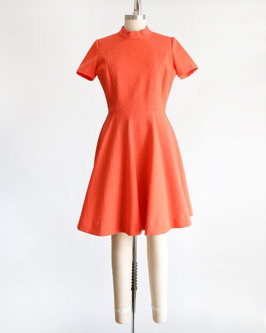 a vintage 1960s coral orange dress on a mannequin against a white background