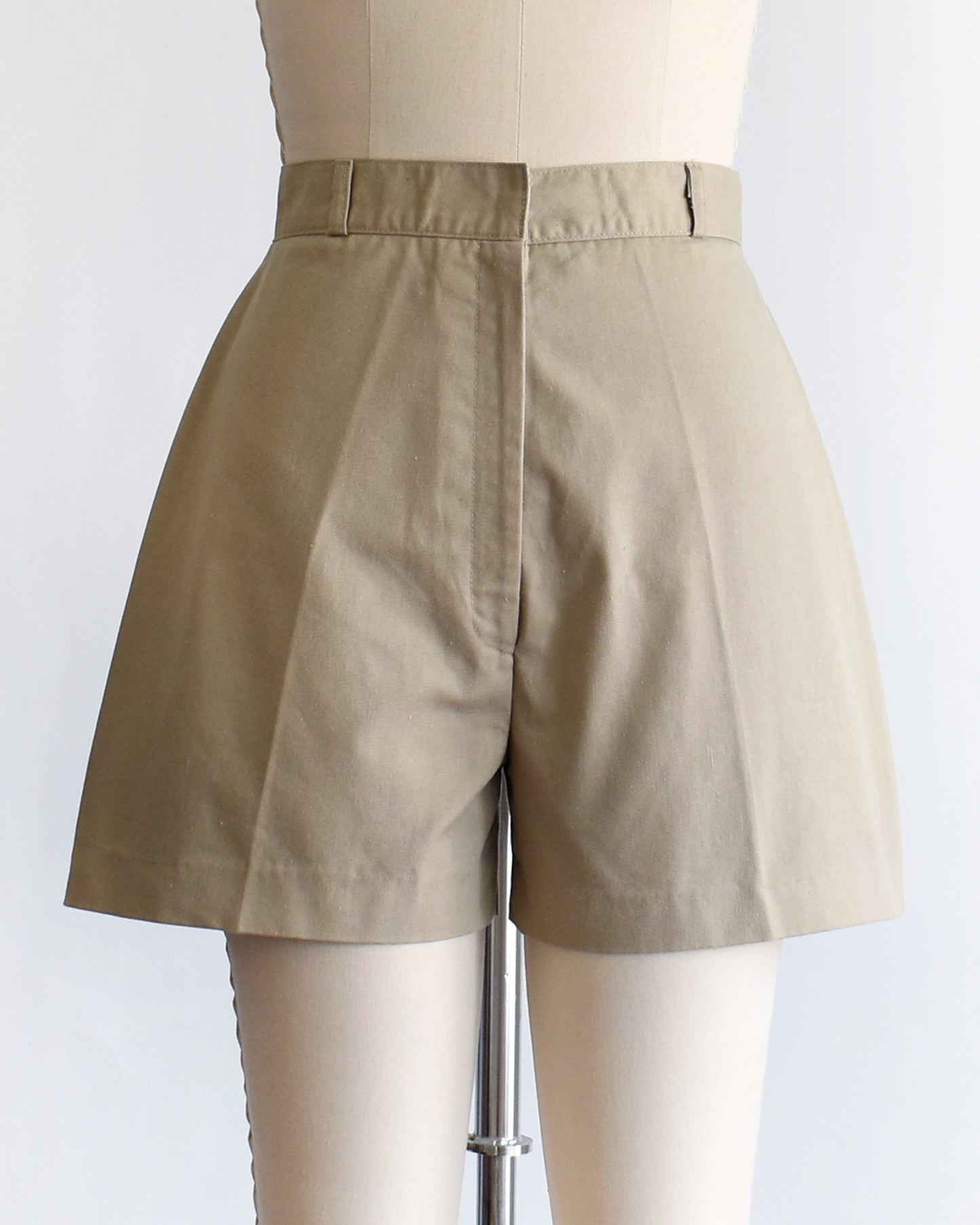 A pair of beige high-waisted shorts displayed on a cream dress form mannequin against a plain white background.
