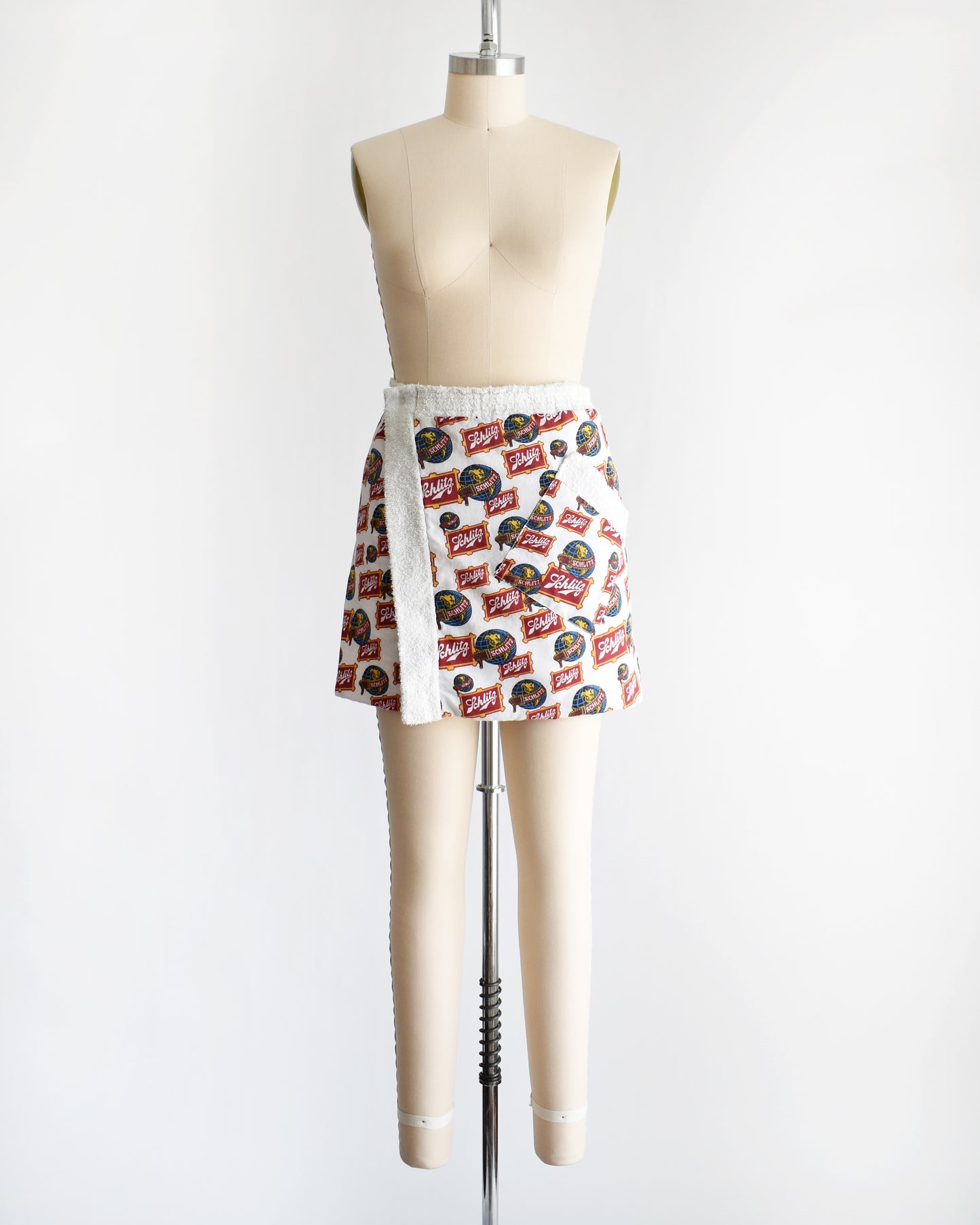 a vintage Schlitz terry cloth wrap towel skirt on a dress form against a white background