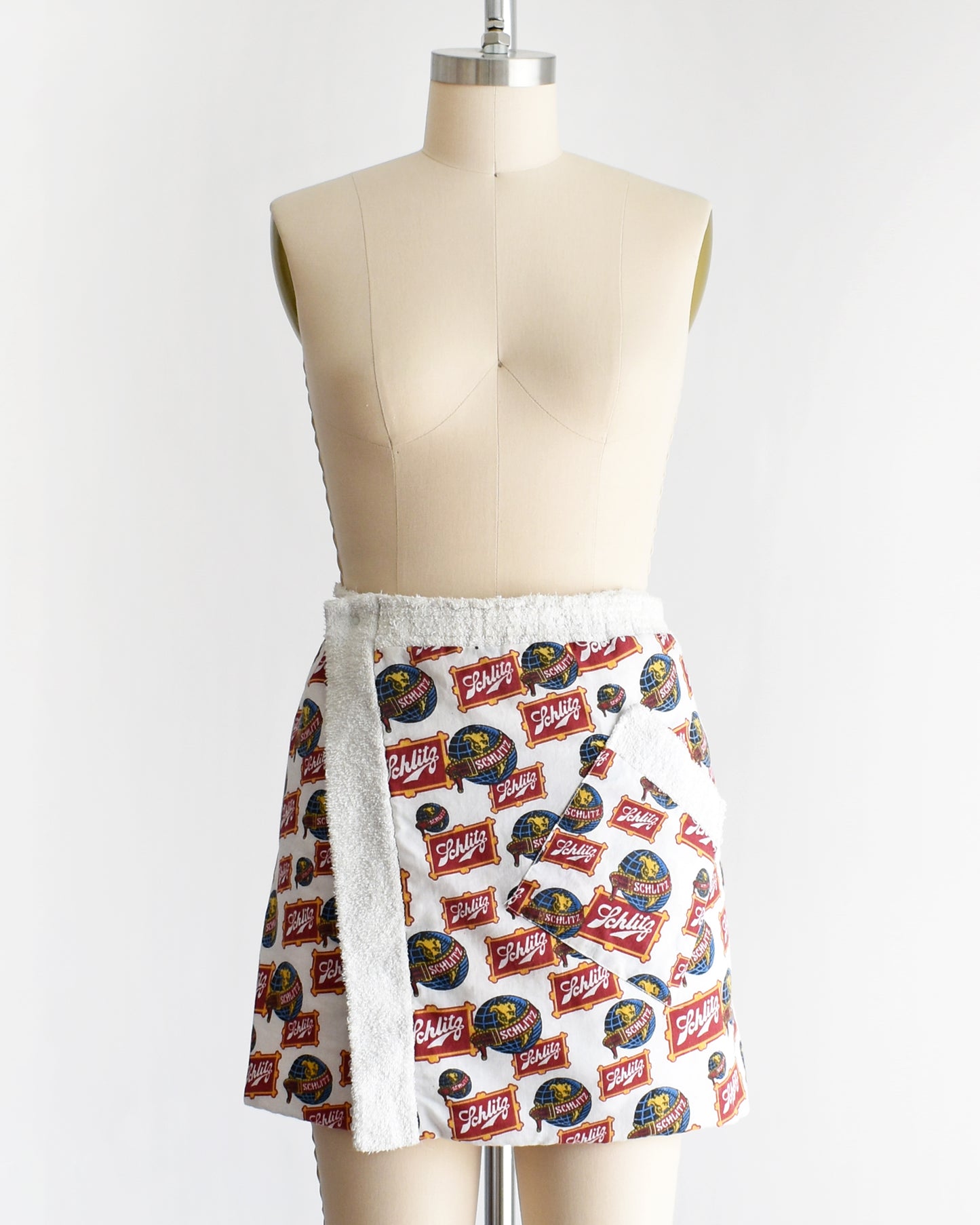 a vintage Schlitz terry cloth wrap towel skirt on a dress form against a white background
