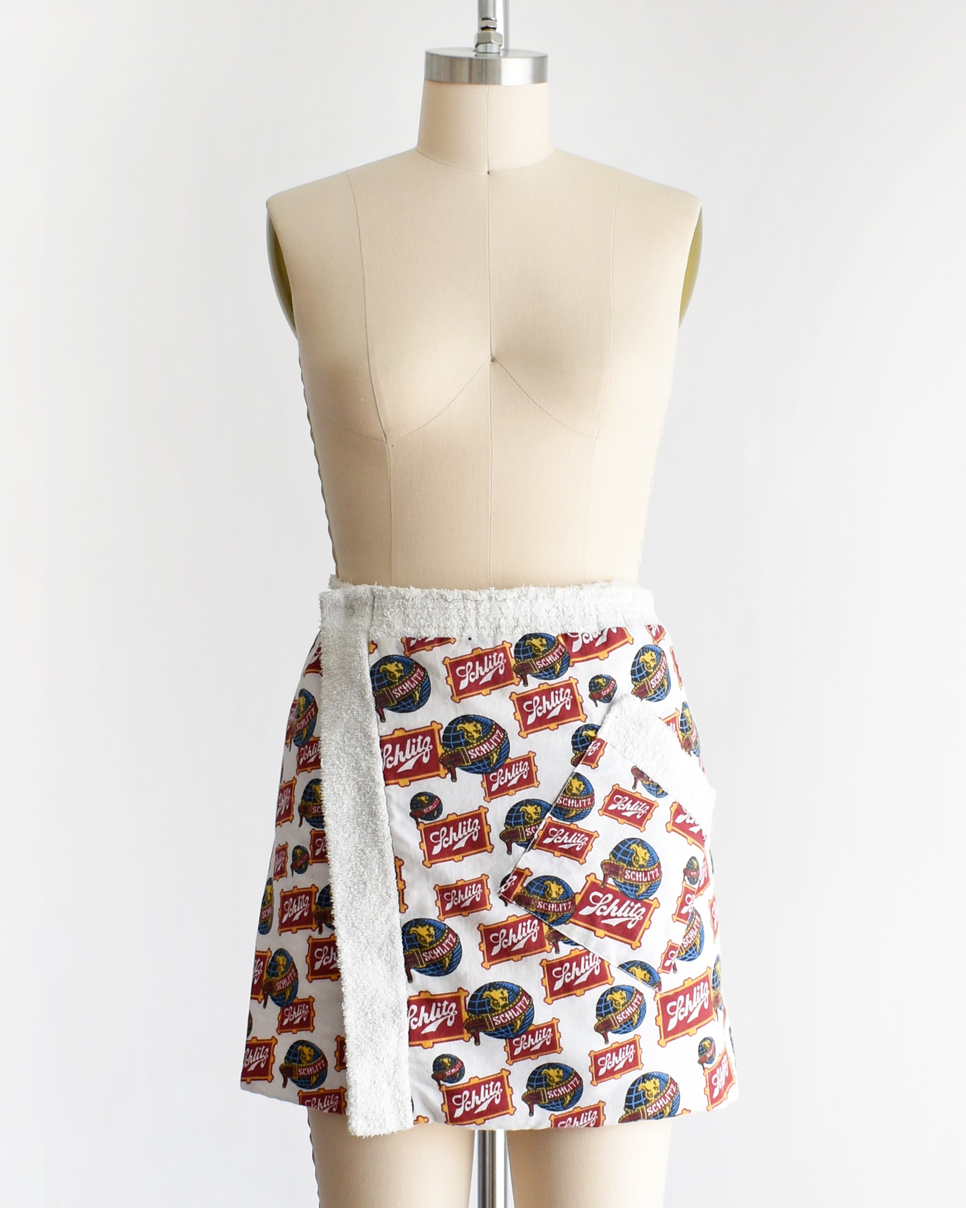 a vintage Schlitz terry cloth wrap towel skirt on a dress form against a white background
