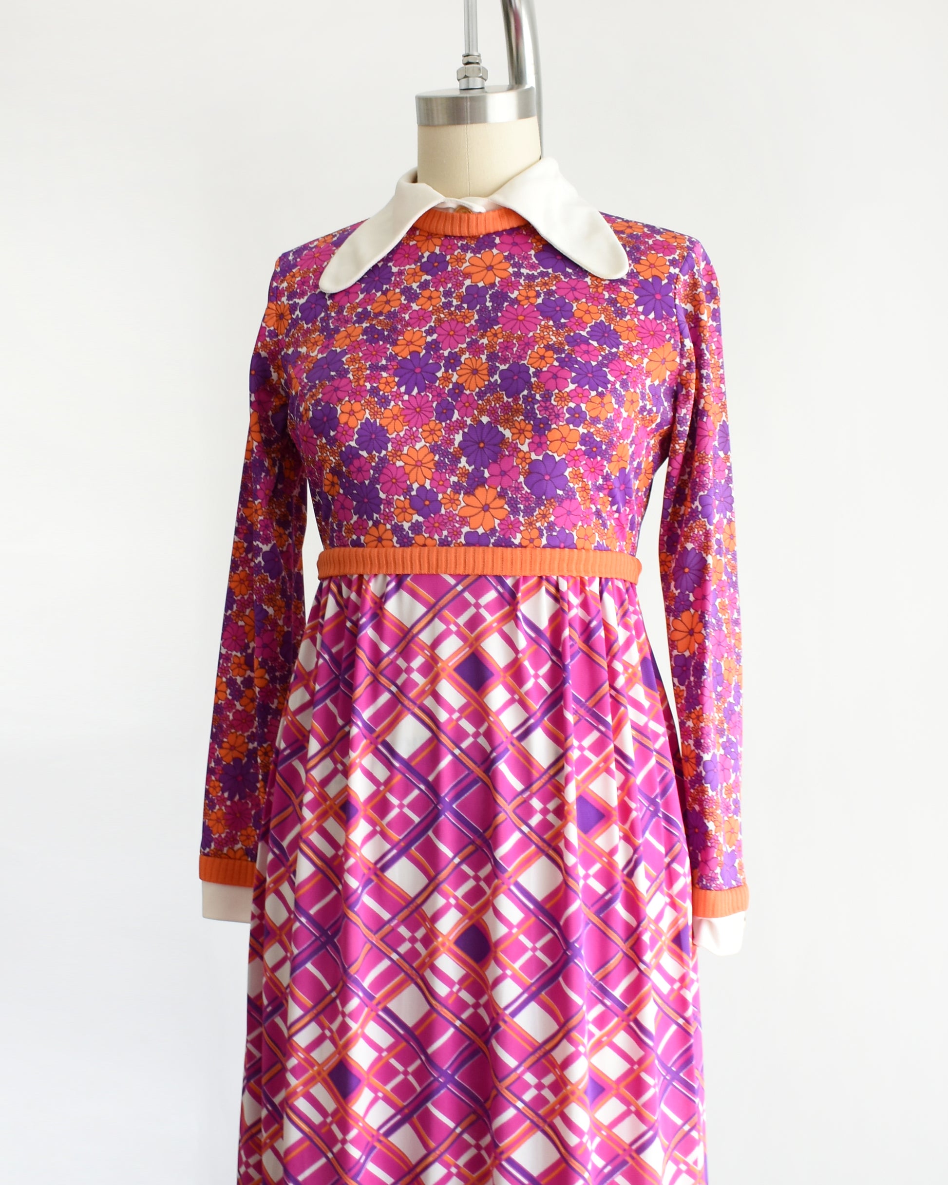 side front view of a vintage 1960s/1970s colorful dress with a floral and geometric pattern on a mannequin against a white background