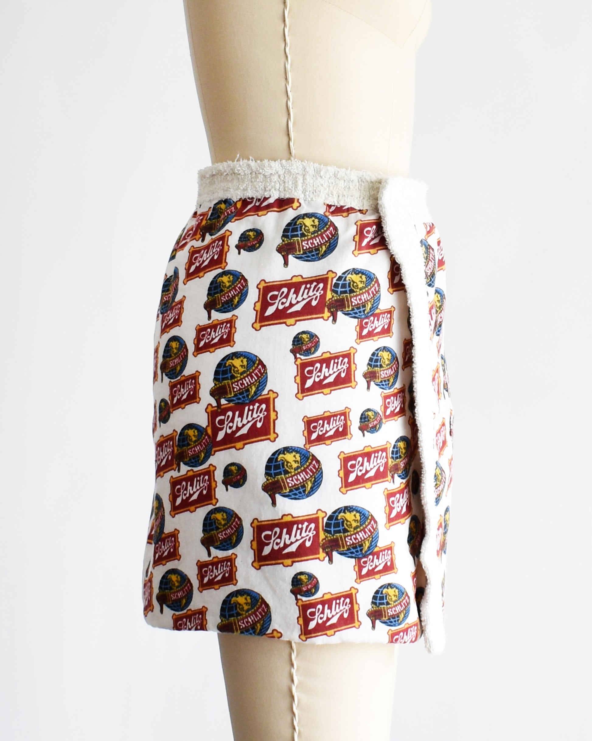 side view of a vintage Schlitz terry cloth wrap towel skirt on a dress form against a white background
