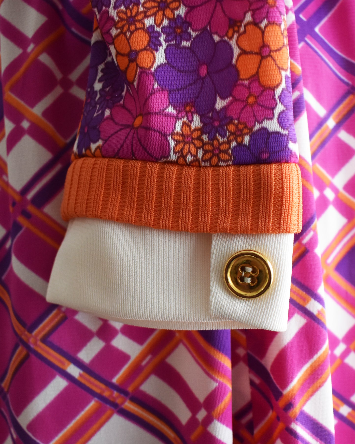 Close-up of the sleeve with floral pattern, orange trim, and gold button.