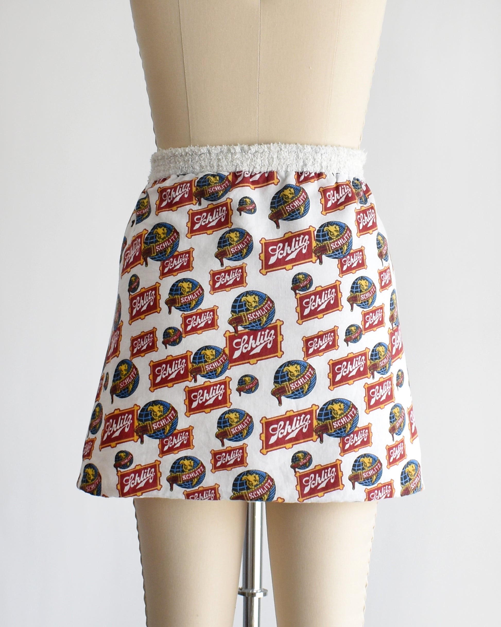 back view of a vintage Schlitz terry cloth wrap towel skirt on a dress form against a white background
