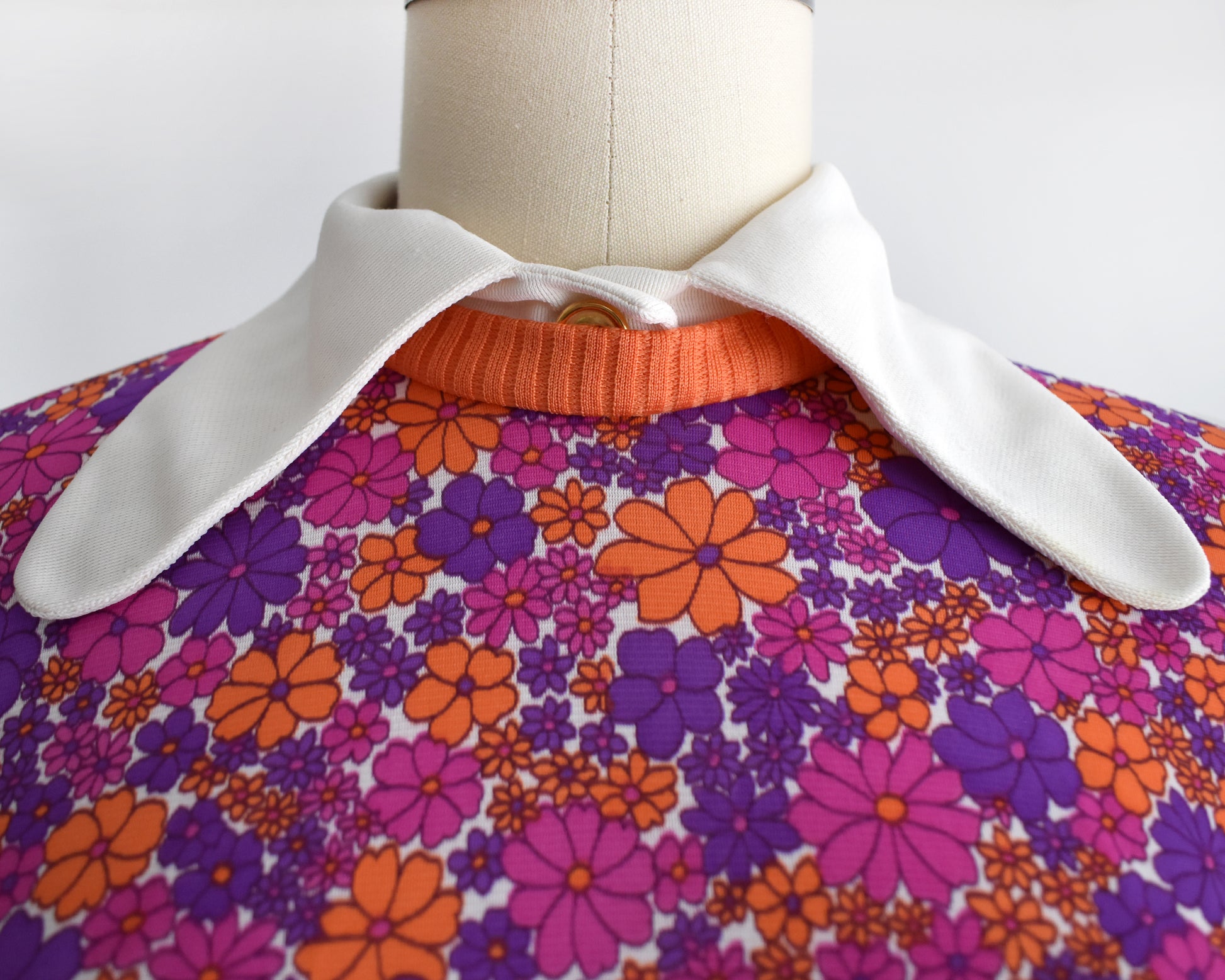 close up of the floral-patterned bodice that has a white collar, orange trim, and decorative button
