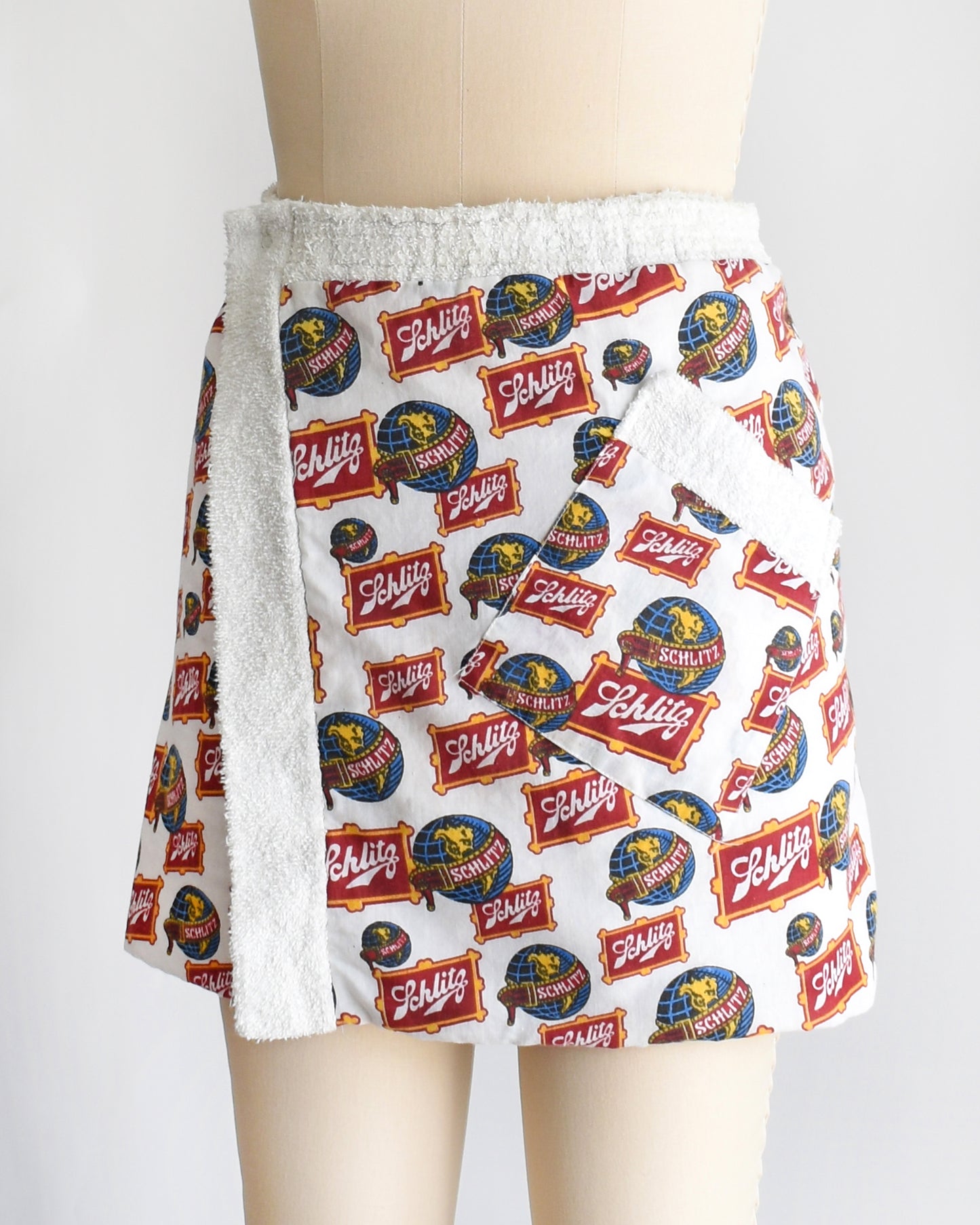 side front view of a vintage Schlitz terry cloth wrap towel skirt on a dress form against a white background