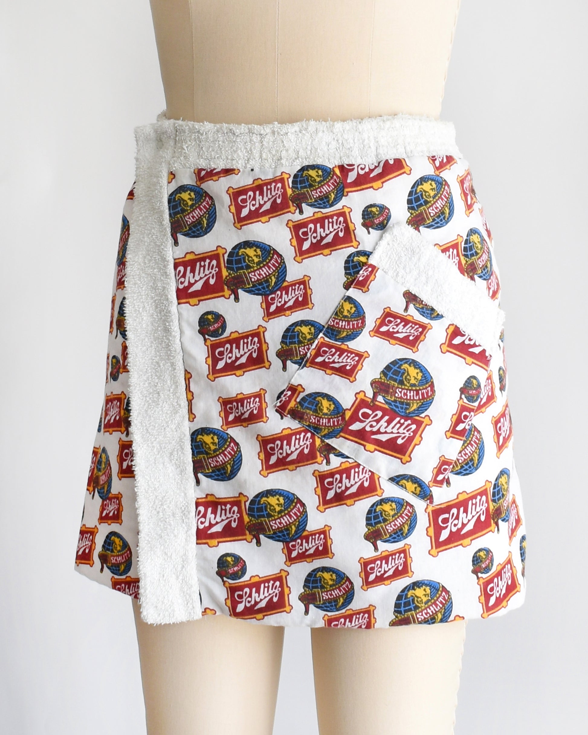 side front view of a vintage Schlitz terry cloth wrap towel skirt on a dress form against a white background