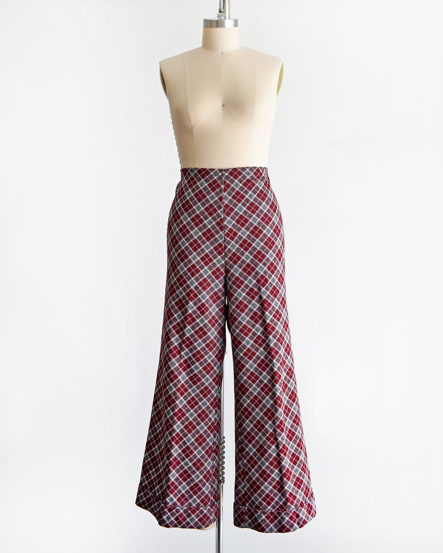 a vintage 1970s burgundy plaid bell bottom pants on a mannequin against a white background