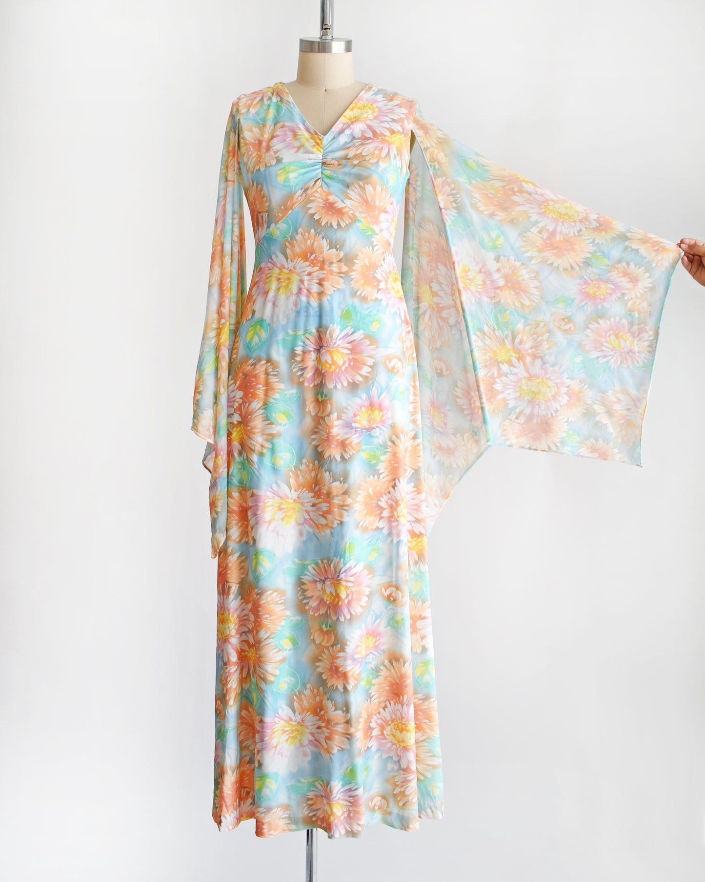 a vintage 1970s floral maxi dress with long angel sleeves being pulled