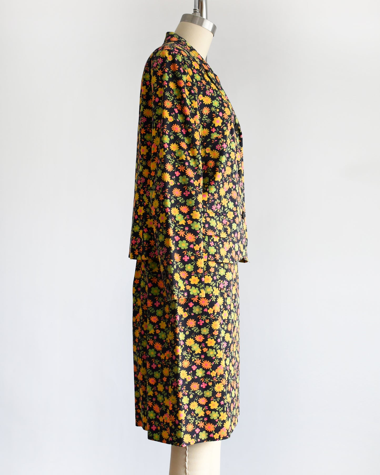 side view of a vintage 1960s/1970s matching floral  blazer and skirt on a mannequin against a white background