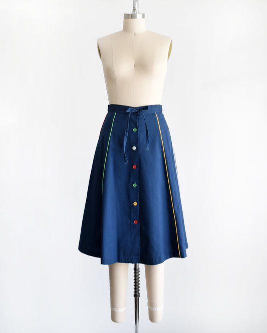 a vintage navy skirt with a multicolor button front and matching stripes on a dress form against a white background