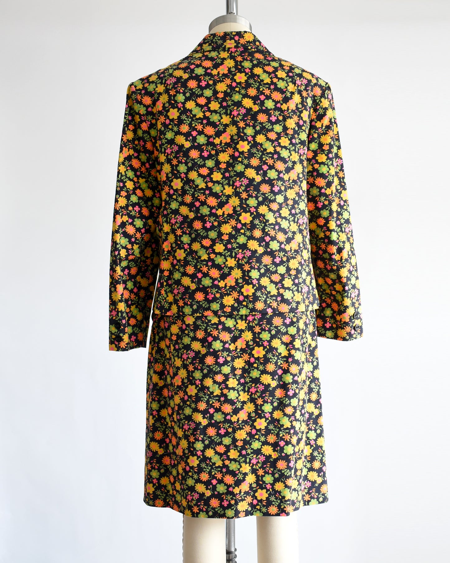 back view of a vintage 1960s/1970s matching floral  blazer and skirt on a mannequin against a white background