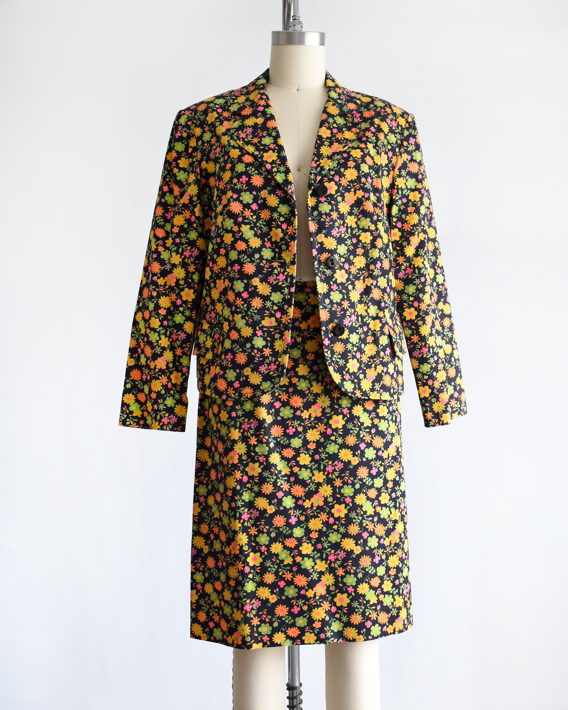 a vintage 1960s/1970s matching floral  blazer and skirt on a mannequin against a white background. the jacket is unbuttoned