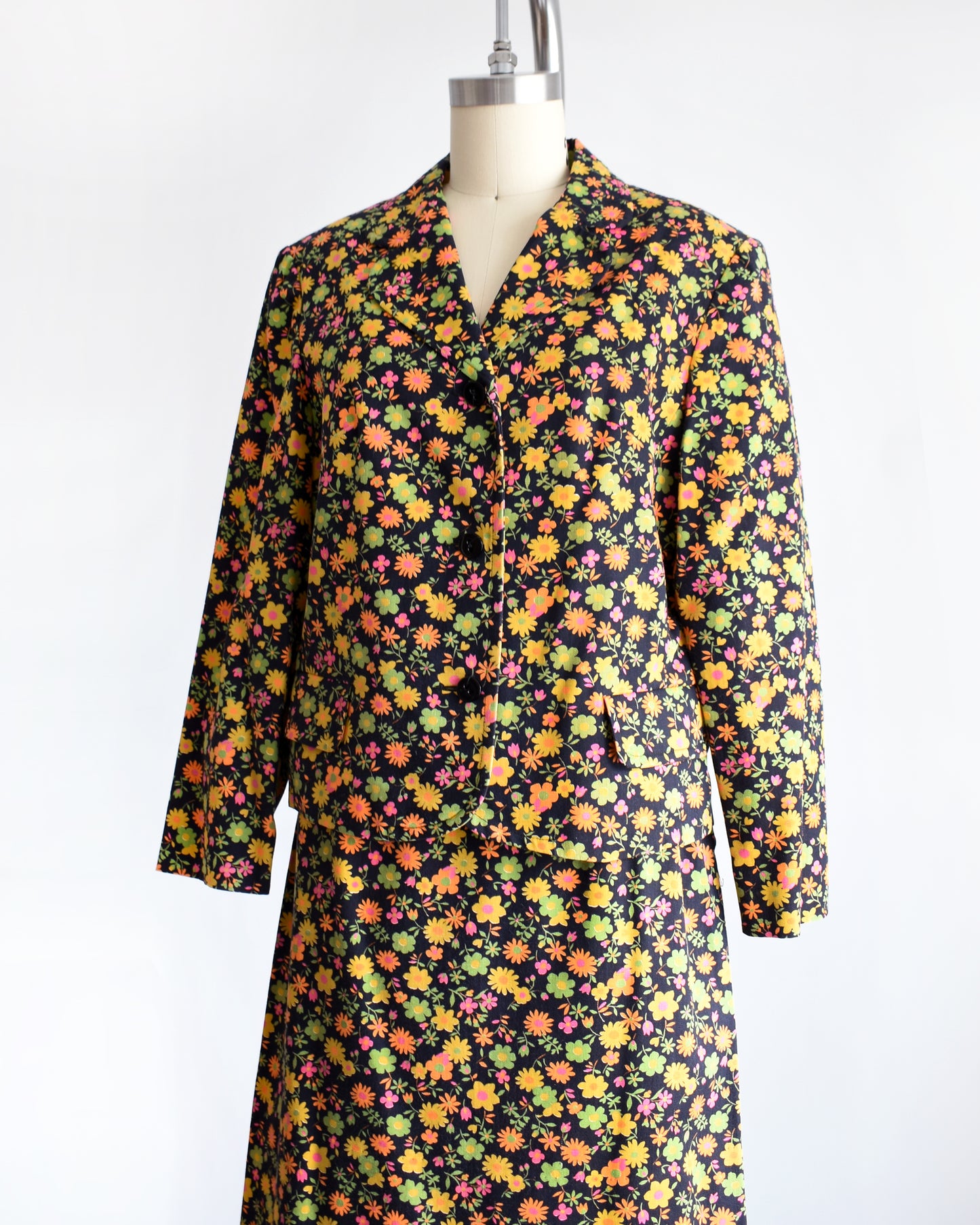 side front view of a vintage 1960s/1970s matching floral  blazer and skirt on a mannequin against a white background