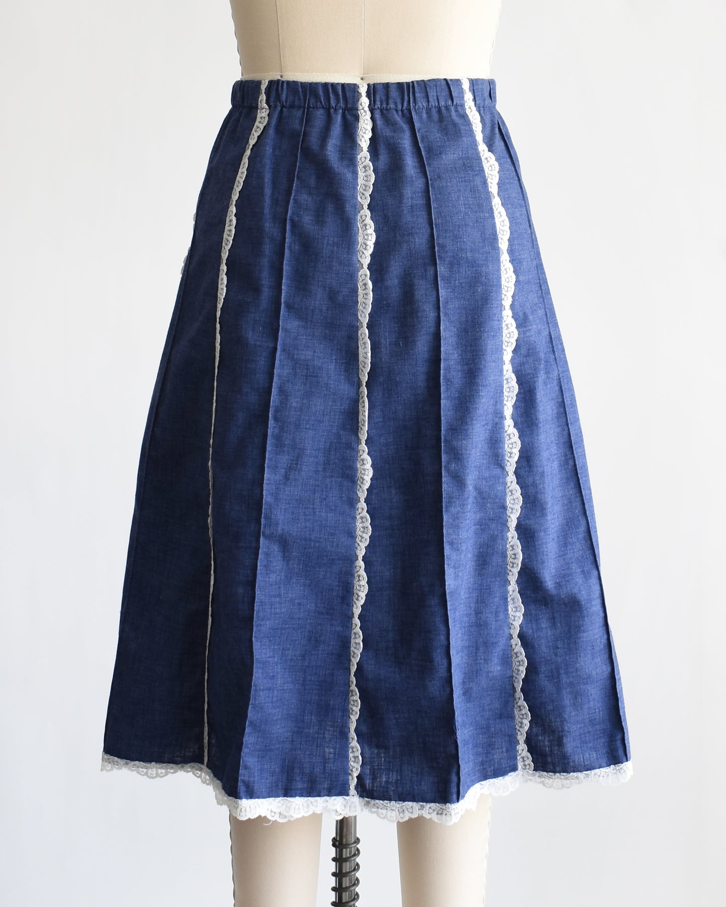 back view of a vintage 1970s blue chambray lace skirt on a dress form against a white background