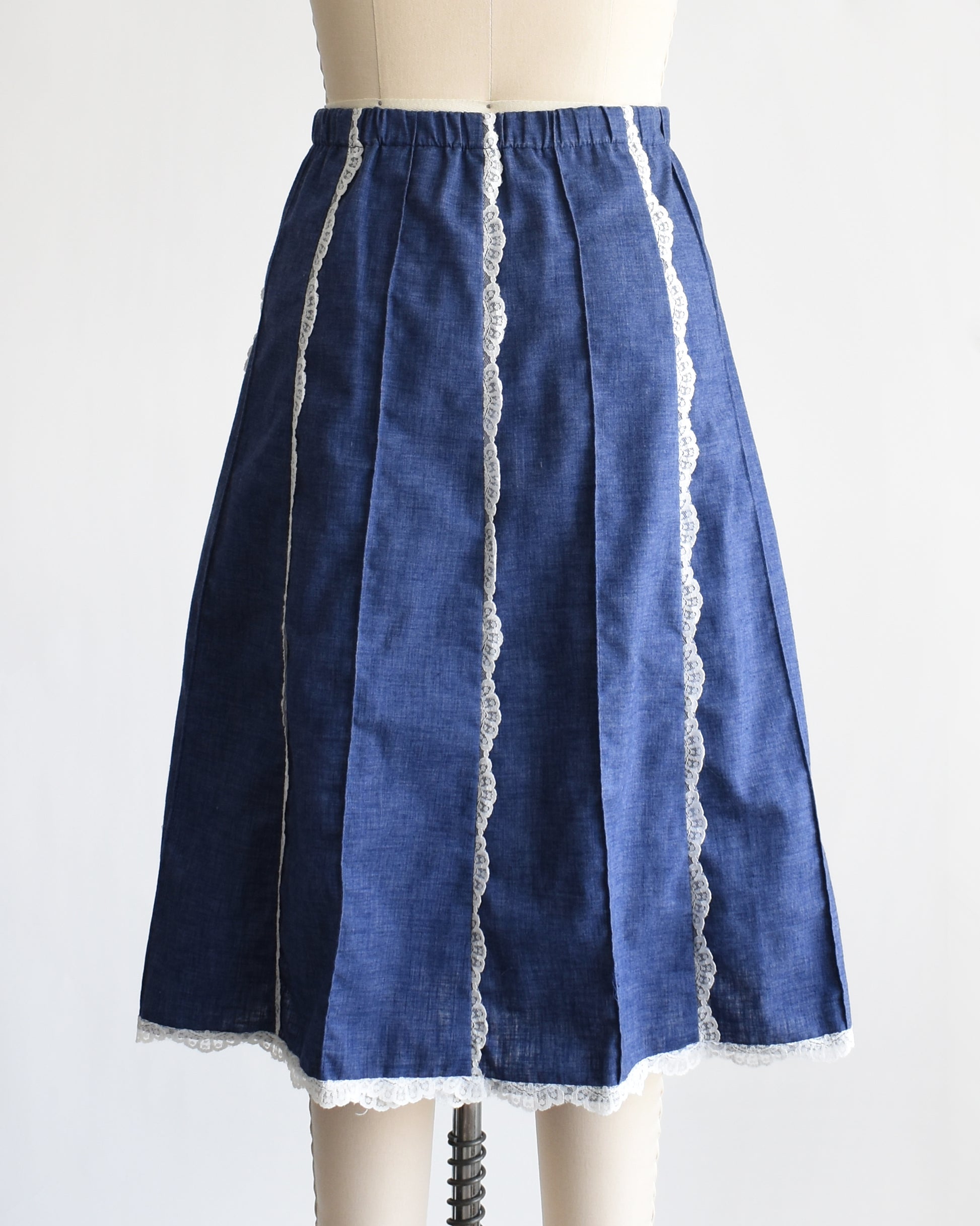 back view of a vintage 1970s blue chambray lace skirt on a dress form against a white background