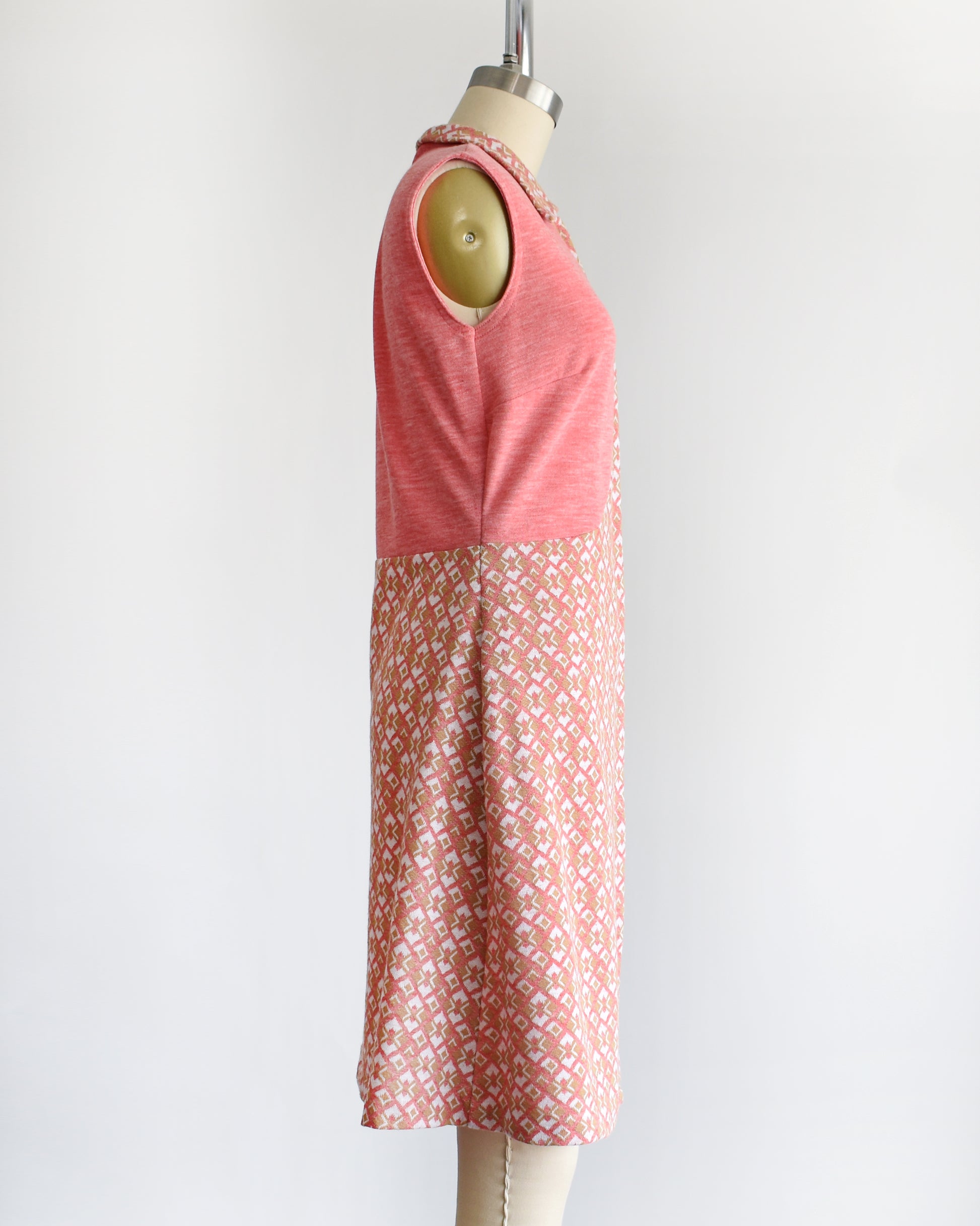 side view of a vintage 1960s/1970s pink sleeveless dress with a geometric pattern on a mannequin against a white background