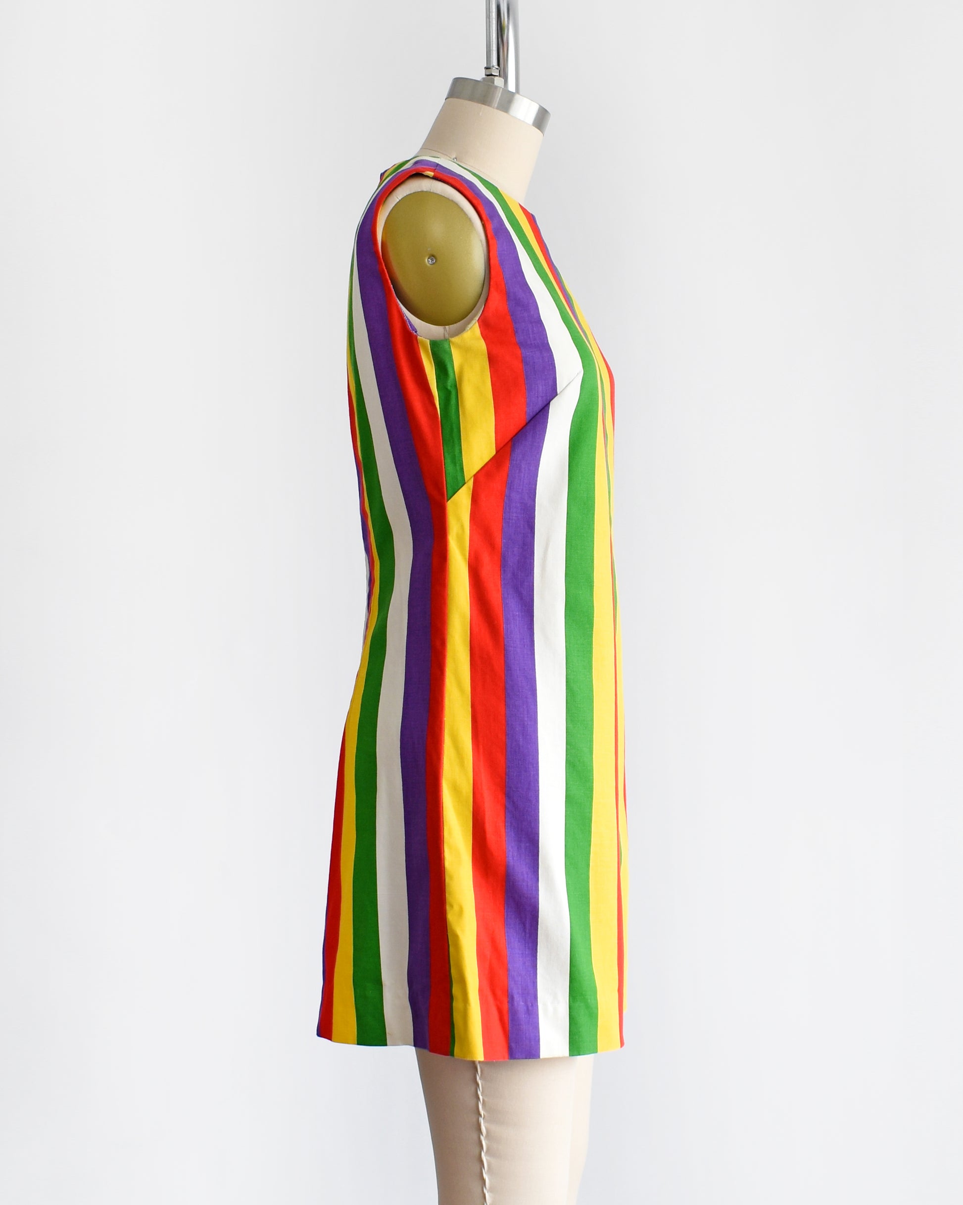 side view of a vintage 1960s rainbow striped romper on a dress form. there is a white belt around the waist which is not included.