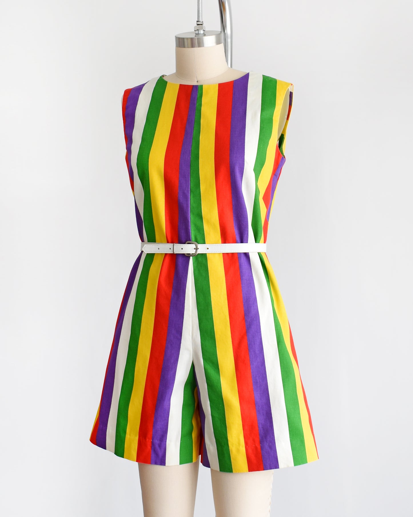 side front view of a vintage 1960s rainbow striped romper on a dress form. there is a white belt around the waist which is not included.