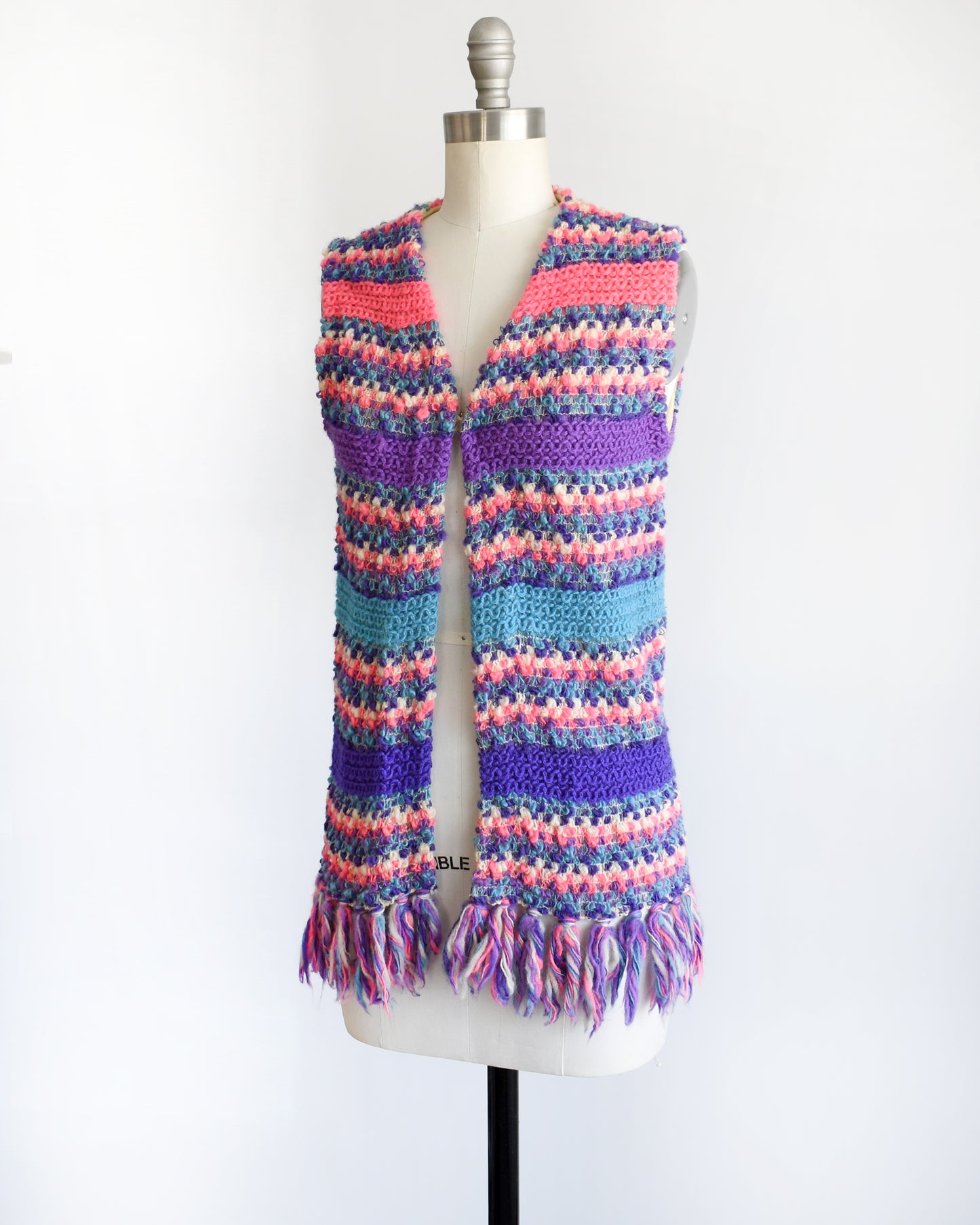side front view of a vintage 1960s/1970s multicolored striped crochet vest on a mannequin against a white background