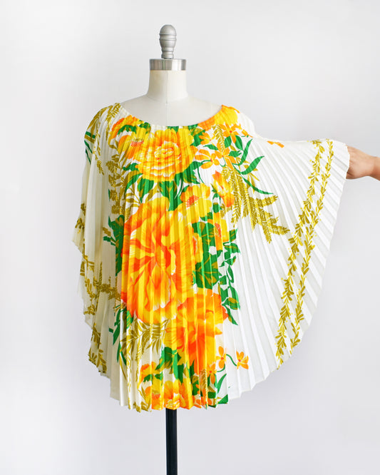a vintage 1970s floral kaftan blouse on a dress form against a white background. the sleeves are pulled out showing the pleats