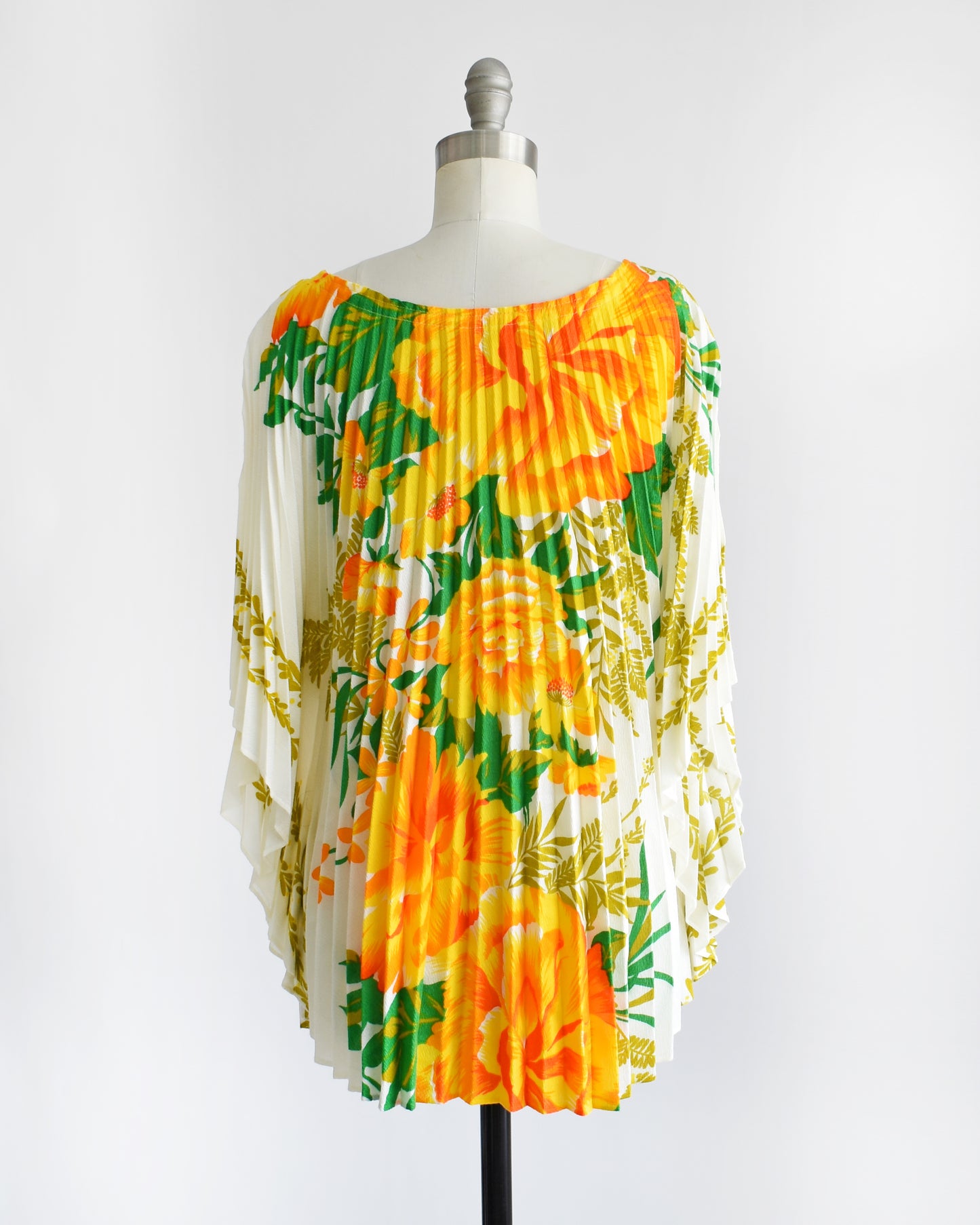 back view of a vintage 1970s floral kaftan blouse on a dress form against a white background