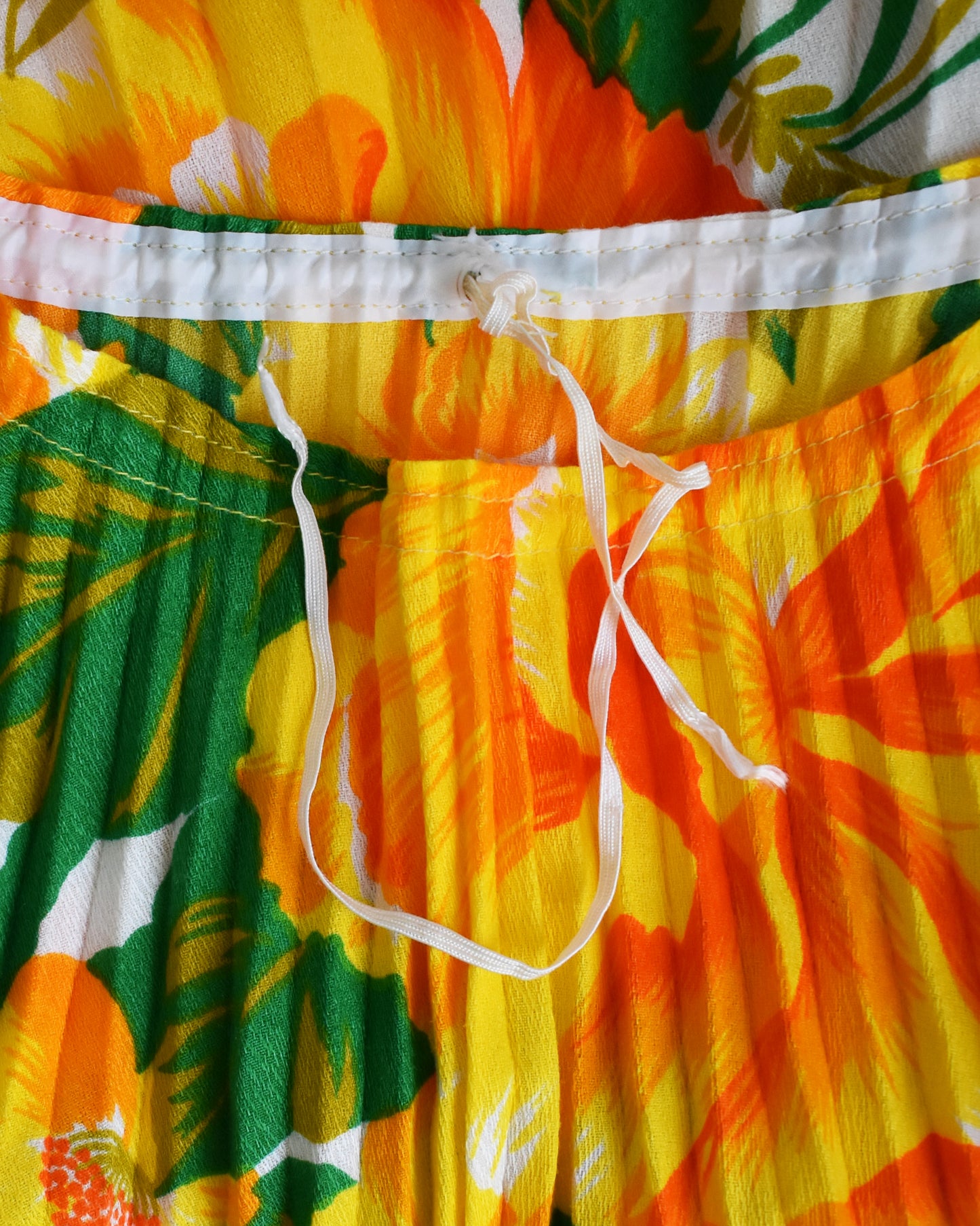 close up of the drawstring neckline on a vintage 1970s floral kaftan blouse on a dress form against a white background