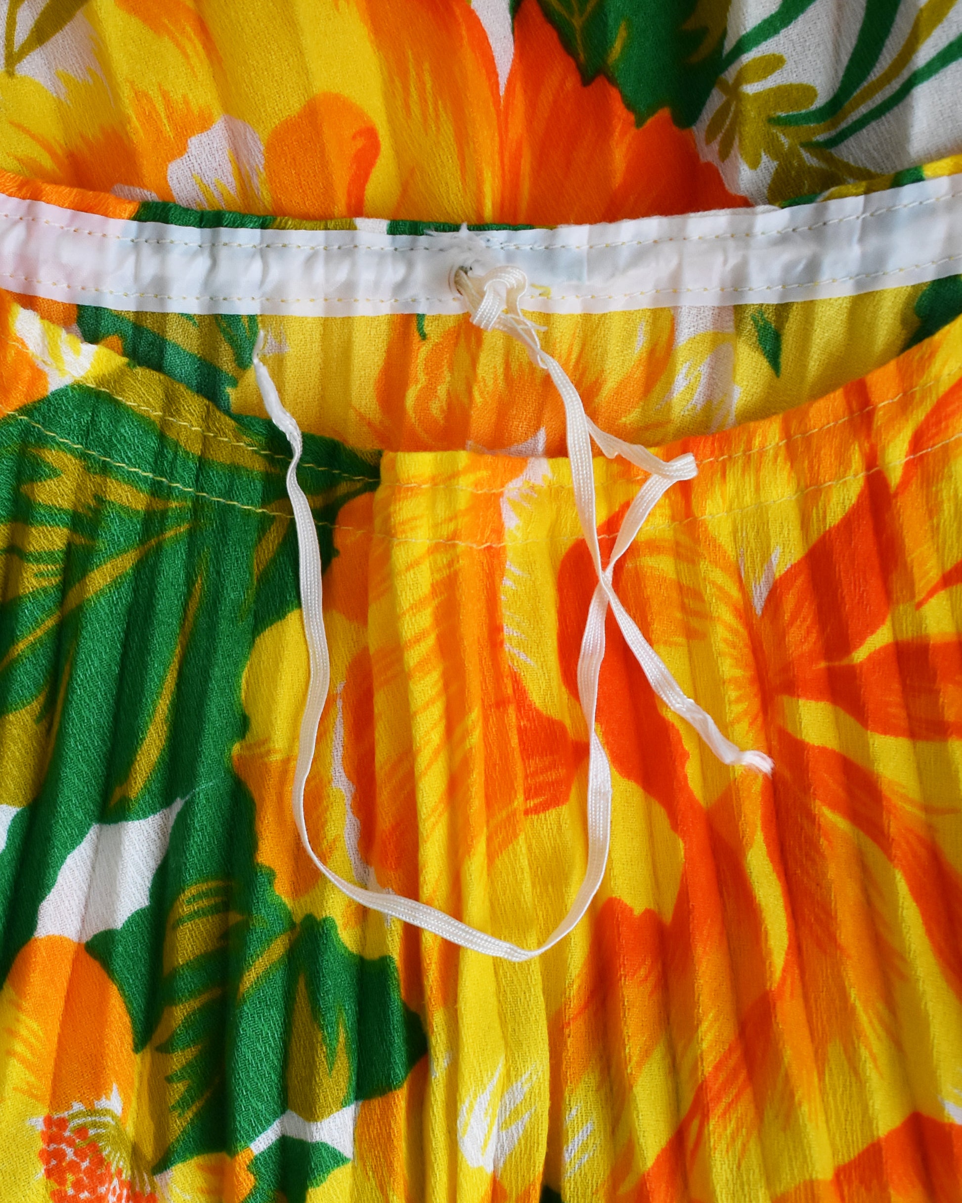 close up of the drawstring neckline on a vintage 1970s floral kaftan blouse on a dress form against a white background