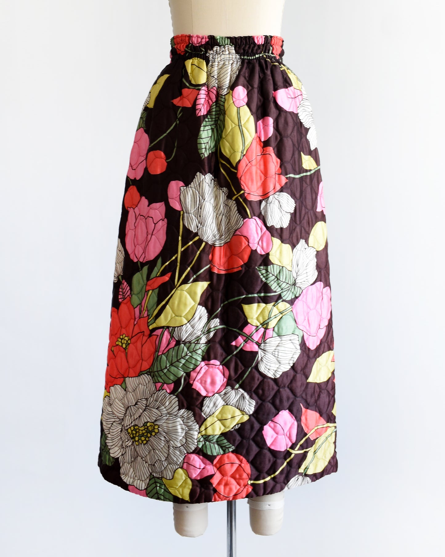a vintage 1970s quilted skit that has a colorful floral print on a mannequin against a white background
