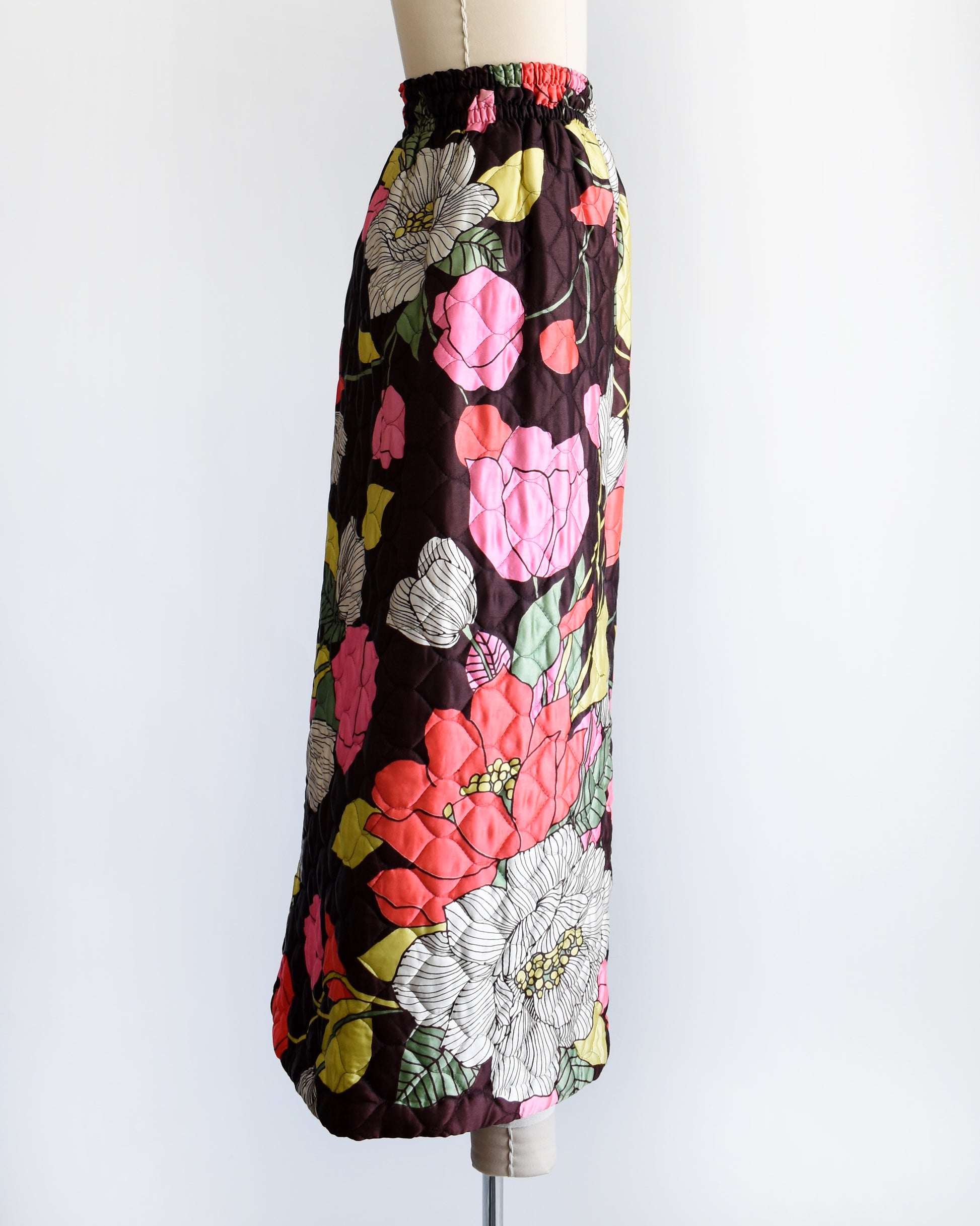 side view of a vintage 1970s quilted skit that has a colorful floral print on a mannequin against a white background