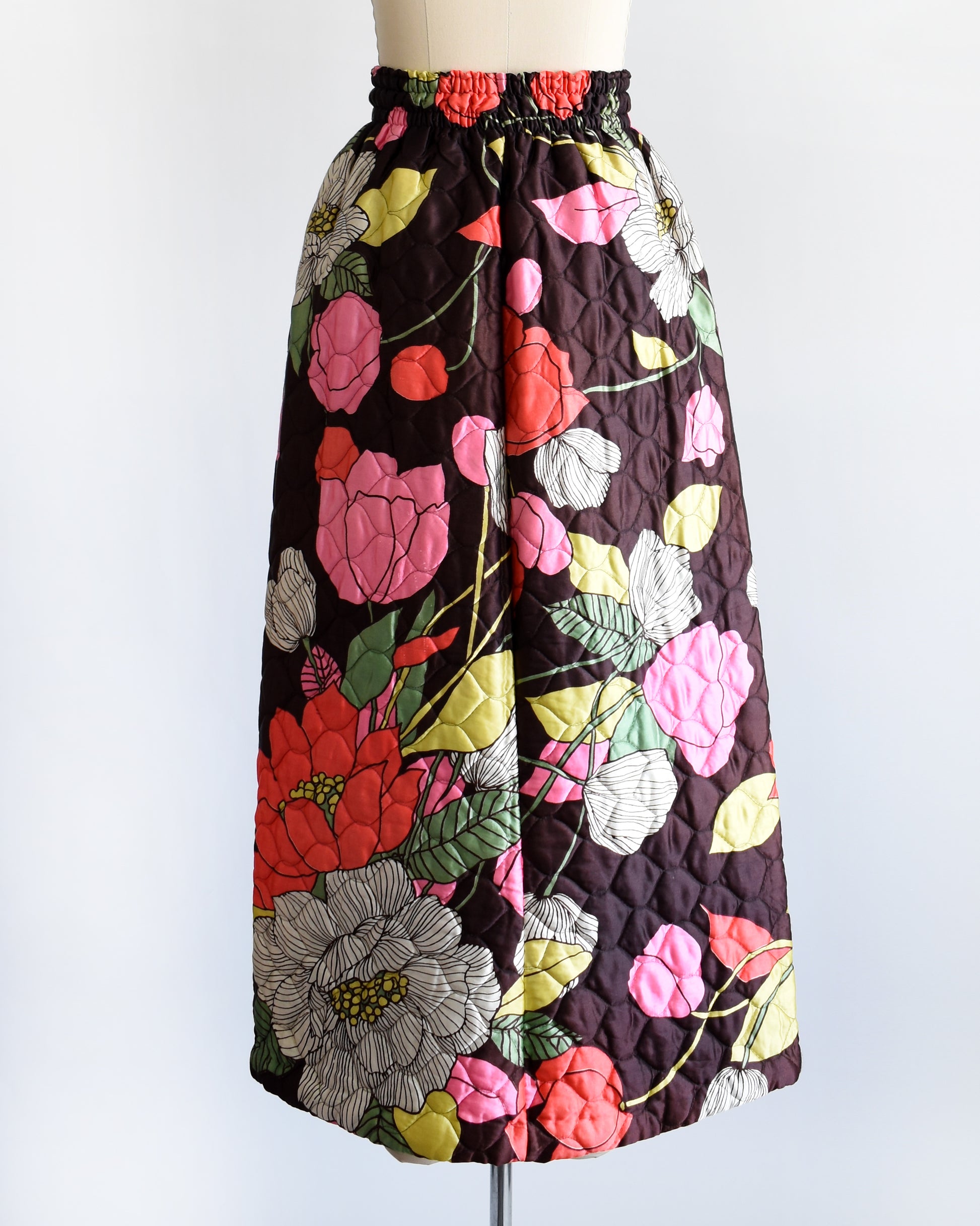 back view of a vintage 1970s quilted skit that has a colorful floral print on a mannequin against a white background
