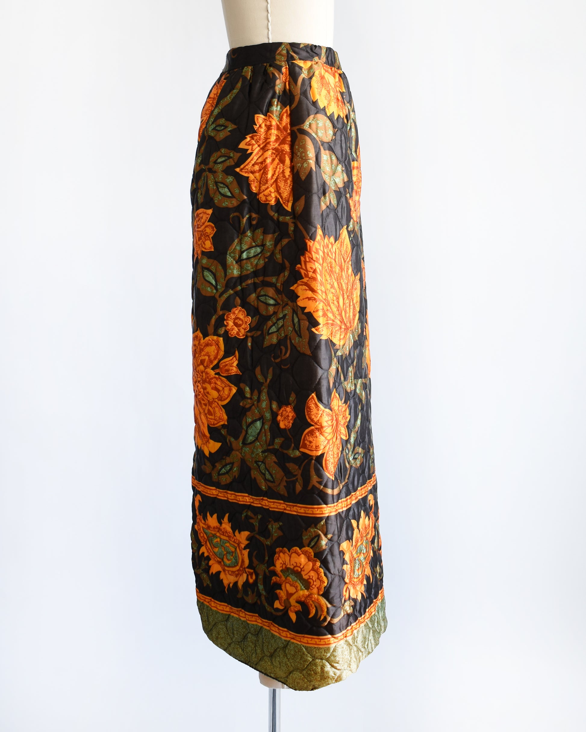 side view of a vintage 1970s dark brown and orange floral patterned maxi skirt on a mannequin against a white background